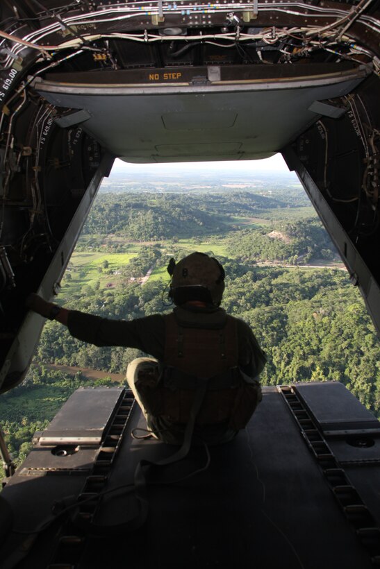 Cpl. Timothy W. Dockum, a mechanic and crew chief for Marine Medium Tiltrotor Squadron 365, holds on tight as an MV-22B Osprey maneuvers over the Belizean countryside, Sept. 10, 2011. Belize offers many training opportunities in various terrains.