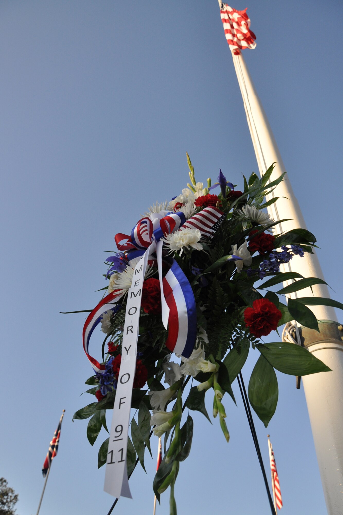 A flower arrangement sits in the shadow of the American Flag in front of the 2nd Bomb Wing Headquarters building at Barksdale Air Force Base, La., Sept. 9, 2011. The arrangement was placed there during a 9/11 Remembrance Ceremony in memory of those lost on 9/11 and both military and civilian losses since Sept. 11, 2001. (U.S. Air Force photo by Tech. Sgt. Jeff Walston/Released)