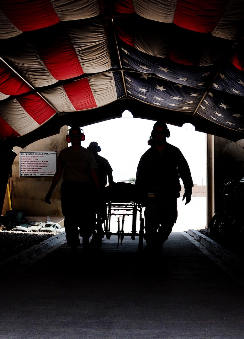 Airmen from the 332nd  Expeditionary Medical Group carry a stretcher under the Hero's Highway flag during  an aeromedical evacuation training exercise. The historical flag was recently cased in a cermony Sept. 1, 2011. (U.S. Air Force photo by Senior Airman Jeffrey Schultze)