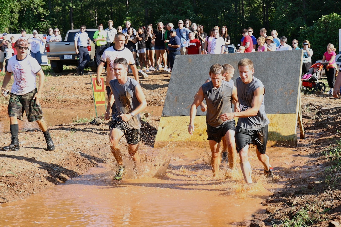 Participants at the Marine Mud Challenge in Belmont, N.C. scramble through a mud pit during the latter part of the seven-mile race here Sept. 10.  Marine reservists (left) direct and encourage competitors through the most grueling part of the race.  Reserve Marines from throughout North Carolina volunteered to help out at this fifth annual event, which attracted more than 800 civilians and military members this year. (Photo courtesy of Betty Oh)