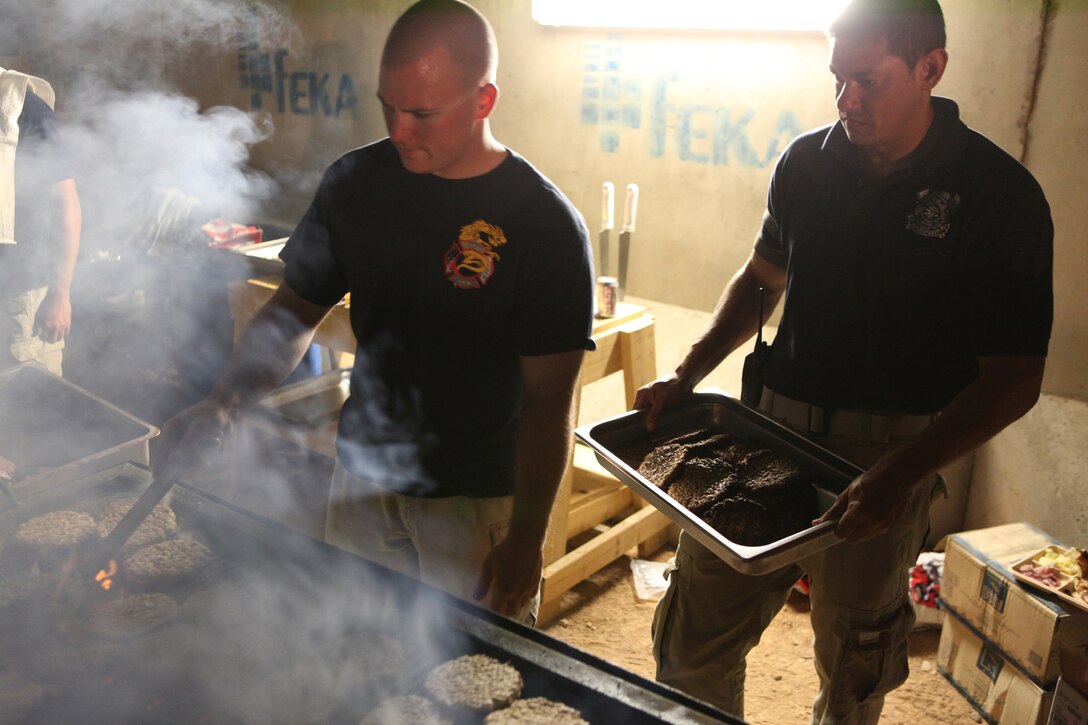 Ryan E. Jones (left), from Seattle, and Marc Fowler (right), from St. Elena Island, S.C., two firefighters with the Camp Leatherneck Fire Department, cook hamburgers during a cookout, Sept. 11, 2011.  Troops from across Regional Command Southwest and firefighters gathered to commemorate the 10th anniversary of the September 11 attacks and to pay respect to those who lost their lives during the event. (Photo by Cpl. Bruno J. Bego)