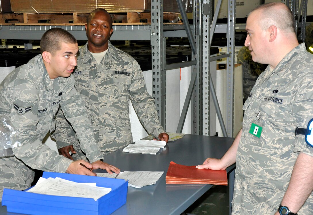 U.S. Air Force Airman 1st Class James McCullough (left), 627th Logistics Readiness Flight, processes paperwork to issue a mobility bag to U.S. Air Force Tech Sgt. Louis Baird (right), 446th Aircraft Maintenance Squadron, as U.S. Air Force Tech Sgt. Curtis Tyler (center), 446th Logistics Readiness Flight, ensures proper procedures are followed during a mobility exercise at McChord Field, Wash. on Sept. 10, 2011. The exercise was the first in preparation for an operational readiness inspection in 2012 which will test the deployment readiness of Reservists from the 446th Airlift Wing. (U.S. Air Force photo/Staff Sgt. Grant Saylor)