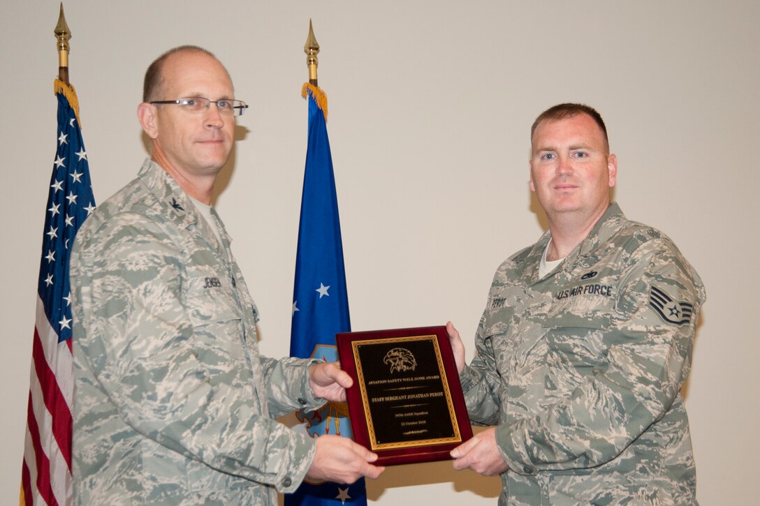 Colonel Jay Jensen, 403rd Wing commander, presents an Aviation Well Done Award to Staff Sgt. Jonathan Perot, 345th Airlift Squadron dedicated crew chief. Mitchell received the award for his part in discovering that some of the installation information regarding the horizontal stabilizer of C-130Js was contradictory to the manufacturer’s specifications. This Air Force-wide issue was corrected based on his actions and those of two other 403rd crew chiefs. (U.S. Air Force photo/Tech. Sgt. Ryan Labadens)