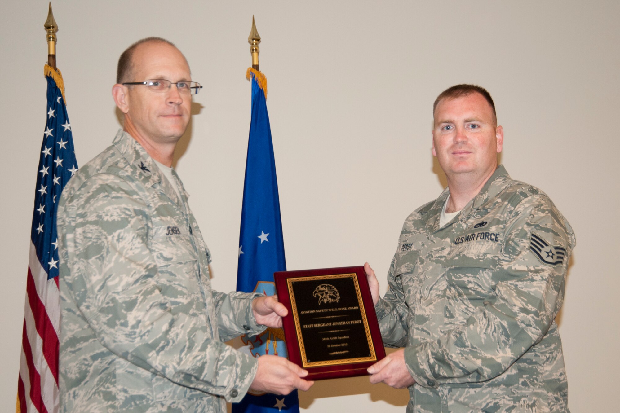 Colonel Jay Jensen, 403rd Wing commander, presents an Aviation Well Done Award to Staff Sgt. Jonathan Perot, 345th Airlift Squadron dedicated crew chief. Mitchell received the award for his part in discovering that some of the installation information regarding the horizontal stabilizer of C-130Js was contradictory to the manufacturer’s specifications. This Air Force-wide issue was corrected based on his actions and those of two other 403rd crew chiefs. (U.S. Air Force photo/Tech. Sgt. Ryan Labadens)