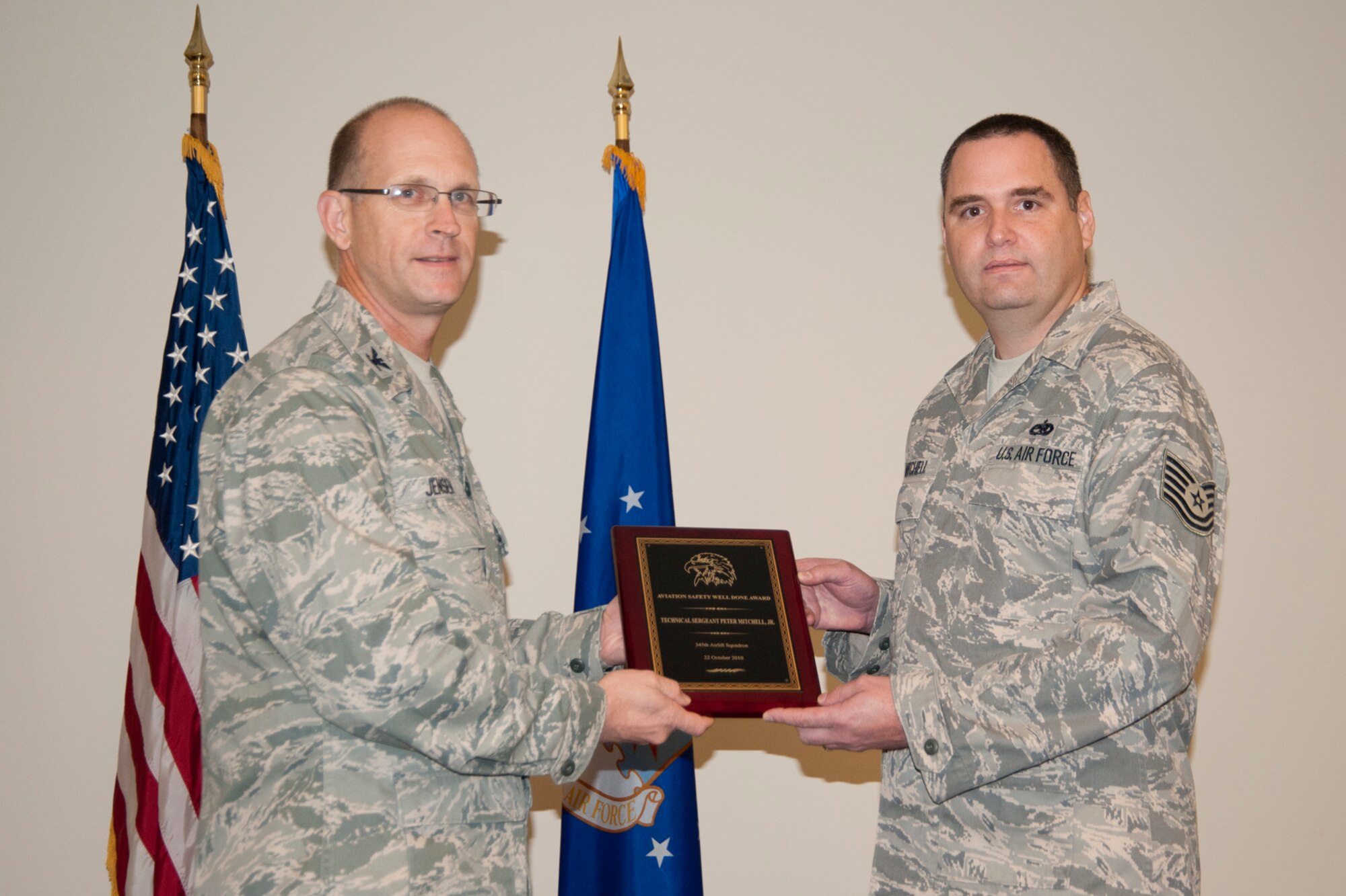 Colonel Jay Jensen, 403rd Wing commander, presents an Aviation Well Done Award to Tech. Sgt. Peter Mitchell, 345th Airlift Squadron aerospace maintenance crew chief. Mitchell received the award for his part in discovering several improper hardware pieces and loose connections on the horizontal stabilizer of C-130Js. This Air Force-wide issue was corrected based on his actions and those of two other 403rd crew chiefs. (U.S. Air Force photo/Tech. Sgt. Ryan Labadens)