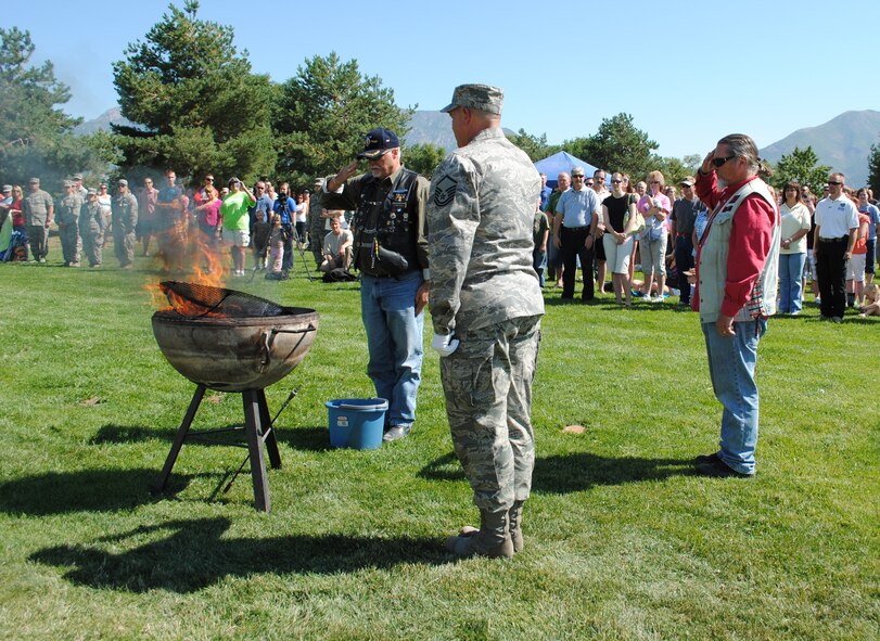 Master Sgt. Dave Graham of the wing’s honor guard and members of the Utah Patriot Guard Riders salute old tattered flags as they are placed in a fire as part of a flag retirement ceremony. (U.S. Air Force photo/Airman 1st Class Crystal Charriere)