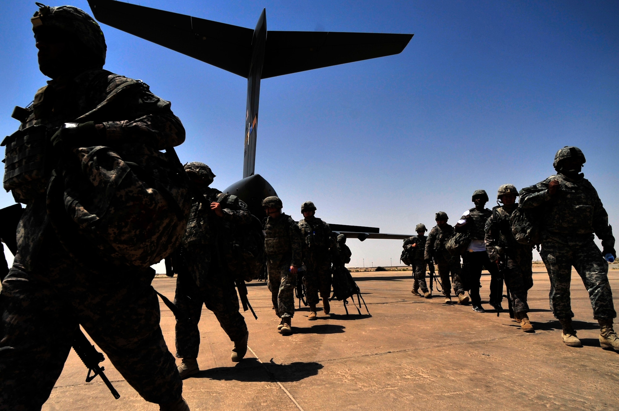 Several military passengers walk off a C-17 Globemaster III transport aircraft at Ali Base, Iraq on Aug. 26, 2011. The terminal is the southern aerial hub of Iraq.  It processes approximately 5,000 passengers and 850,000 pounds of cargo each month. (U.S. Air Force photo/Master Sgt. Cecilio Ricardo)