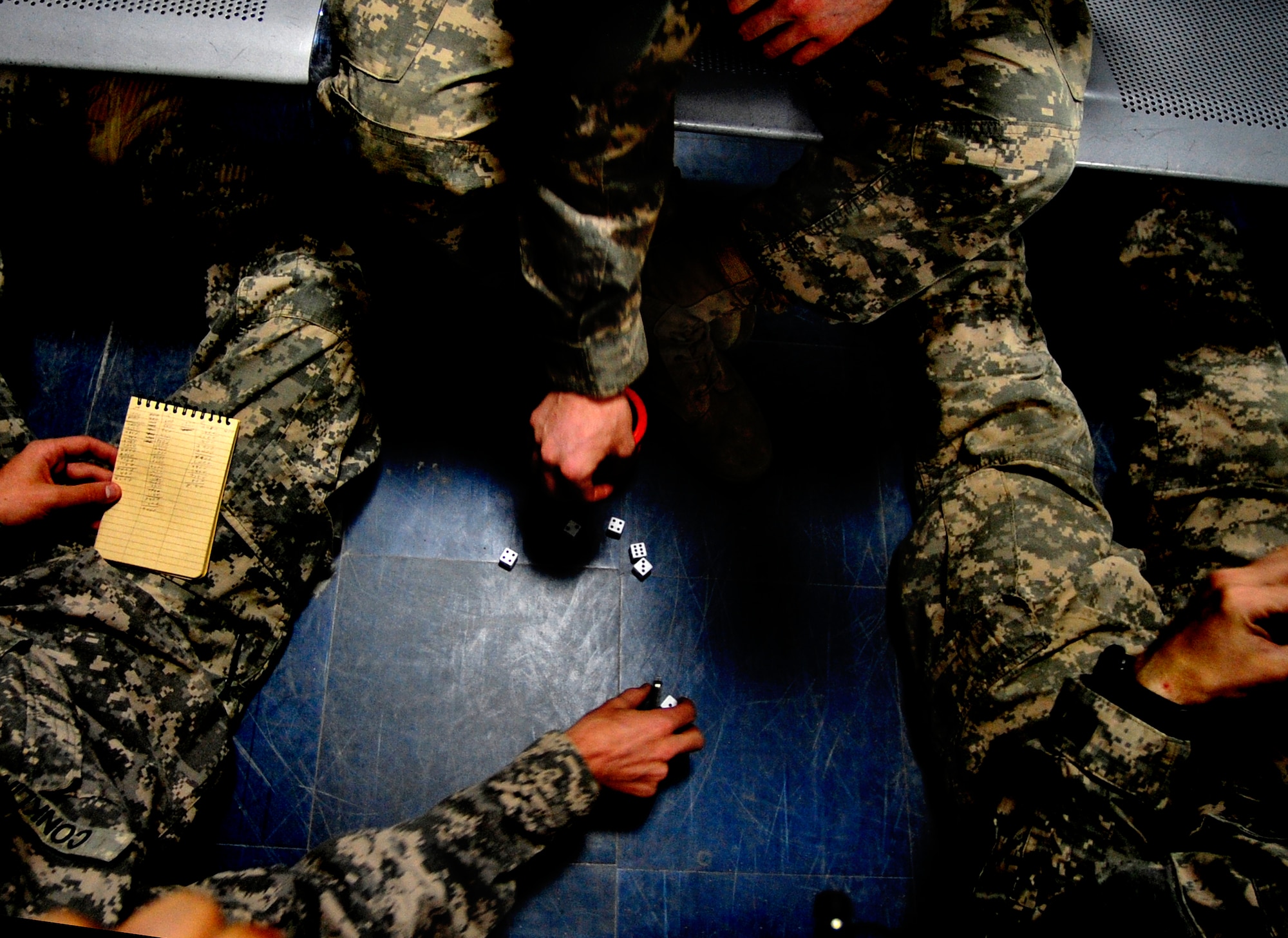 Three soldiers play a Farkle dice game while waiting for transport at the passenger terminal Ali Base, Iraq on Aug. 26, 2011. The terminal is the southern aerial hub of Iraq.  It processes approximately 5,000 passengers and 850,000 pounds of cargo each month. (U.S. Air Force photo/Master Sgt. Cecilio Ricardo)