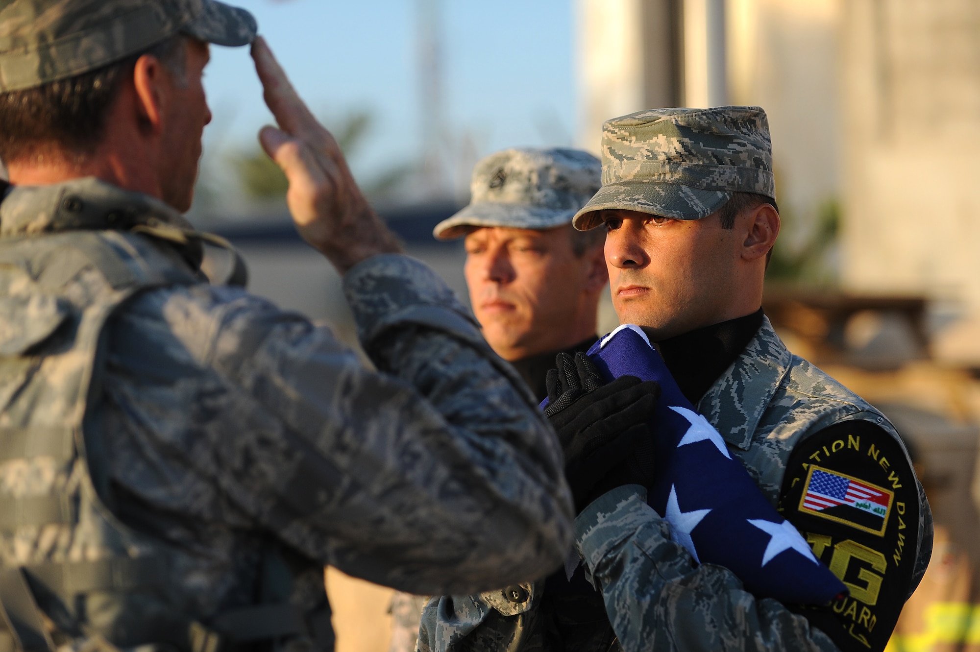 Brig. Gen. Anthony Rock, 321st Air Expeditionary Wing commander, salutes the U.S. flag held by Staff Sgt. Anthony Inauen, 447th Expeditionary Communications Squadron, during a remembrance ceremony Sept. 11, 2011, at Sather Air Base, Iraq, in honor of the tenth anniversary of the attacks. More than 100 Soldiers, Sailors Airmen and civilians who took part in a remembrance march in full battle rattle. The two-mile march, split up into groups of 10, honored those who lost their lives during the attacks at the World Trade Center, the Pentagon and in Shanksville, Pa. (U.S. Air Force photo/Staff Sgt. Mike Meares)