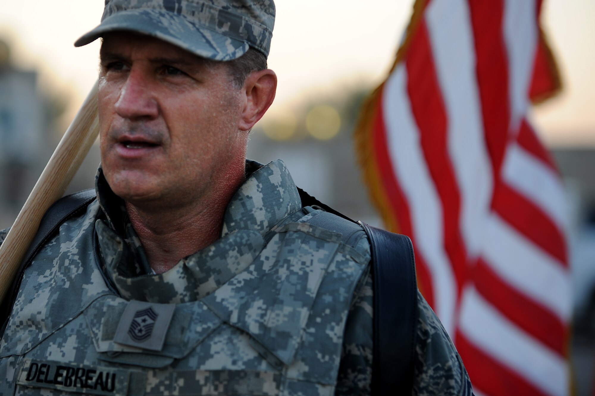 Chief Master Sgt. Gerald Delebreau, 321st Air Expeditionary Wing command chief master sergeant, walks to hand off the wing's U.S. flag to the next group of more than 100 Soldiers, Sailors Airmen and civilians who took part in a remembrance march in full battle rattle Sept. 11, 2011, in honor of the 10th anniversary of the attacks. The two-mile march, split up into groups of 10, honored those who lost their lives during the attacks at the World Trade Center, the Pentagon and in Shanksville, Pa. the chief made sure each group had the opportunity to carry the flag across the finish line. (U.S. Air Force photo/Staff Sgt. Mike Meares)