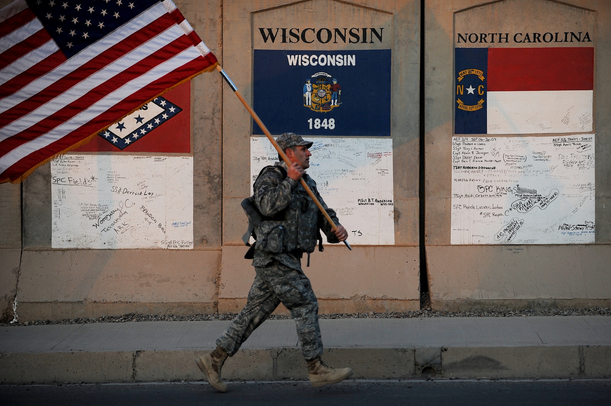 Chief Master Sgt. Gerald Delebreau, 321st Air Expeditionary Wing command chief master sergeant, sprints in full body armor to hand off the wing's U.S. flag to the next group of more than 100 Soldiers, Sailors Airmen and civilians who took part in a remembrance march in full battle rattle Sept. 11, 2011, in honor of the 10th anniversary of the attacks. The two-mile march, split up into groups of 10, honored those who lost their lives during the attacks at the World Trade Center, the Pentagon and in Shanksville, Pa. (U.S. Air Force photo/Staff Sgt. Mike Meares)