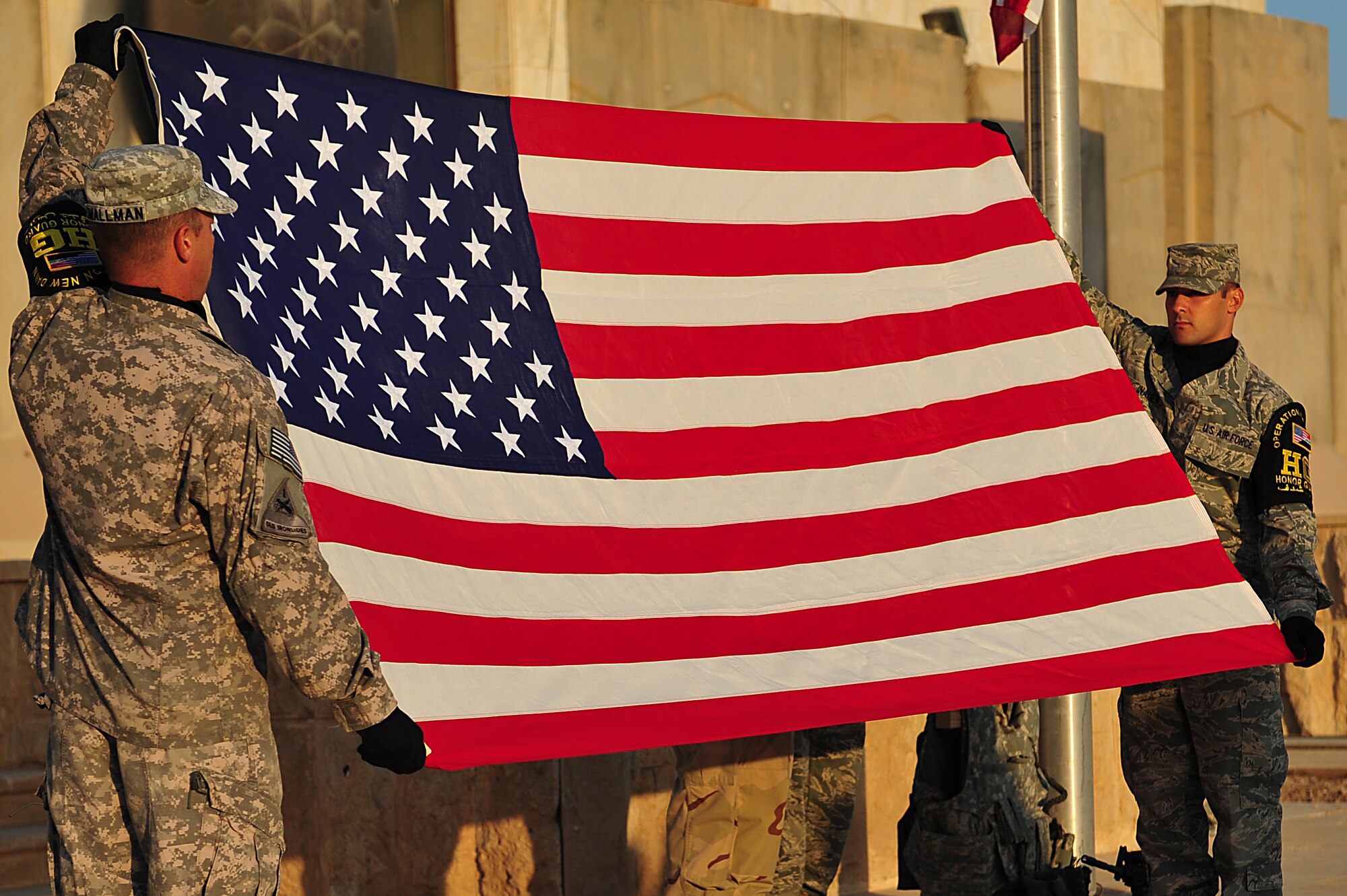 Honor guard members display the U.S. flag during a flag folding ceremony after a two-mile road march, honoring the 9/11 attacks tenth anniversary at Sather Air Base, Iraq, Sept. 11, 2011. More than 100 Soldiers, Sailors, Airmen and civilians donned their body armor and took part in the march as the sun rose. (U.S. Air Force photo/Tech. Sgt. Josef Cole)