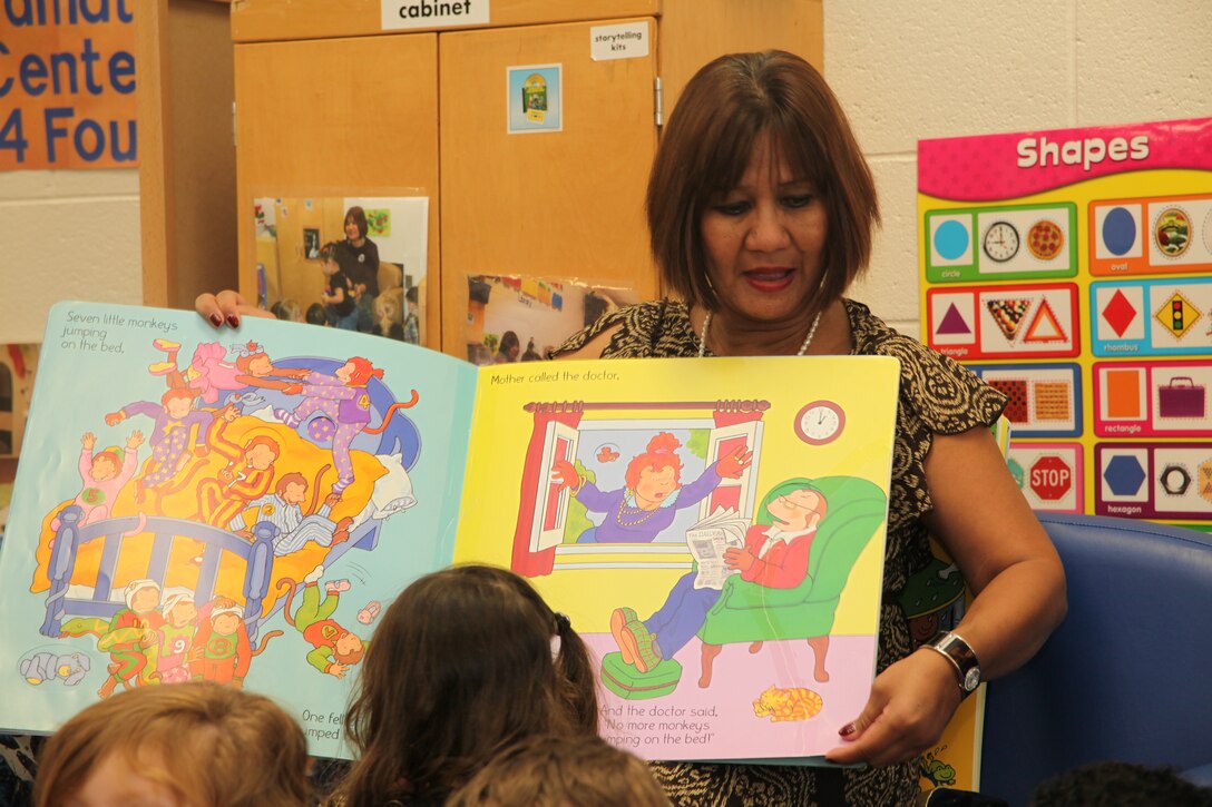 Carolina Lauer, a program assistant with Marine Corps Community Services Child Development Center here, and students read along to the book “No More Monkeys Jumping on the Bed,” in Lauer’s last class before her retirement, Sept. 12. Lauer retired after 14 years at the station CDC.