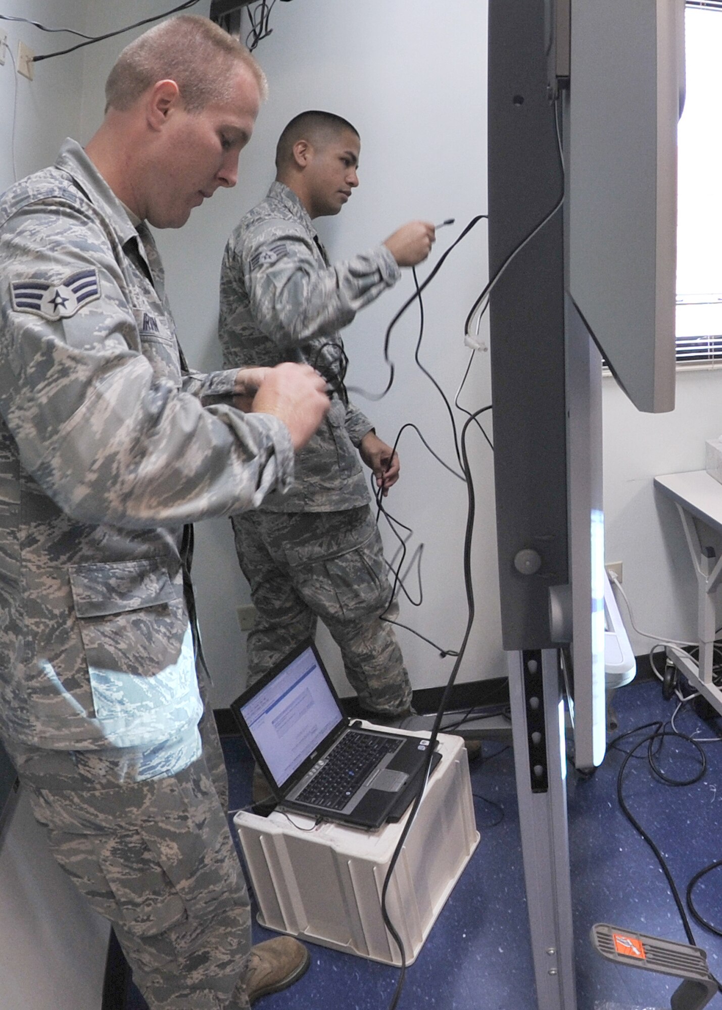 ANDERSEN AFB, Guam—Senior Airman Scott Irwin and Senior Airman Jeremy Quinata of the 644th Combat Communication Squadron, put together a Smart Board in a class room at the elementary school here Sept. 9. Volunteers from the 644 CBCS visited the Andersen Elementary School to setup a new computer lab and Smart Boards for students. (U.S. Air Force photo by Staff Sgt. Alexandre Montes)