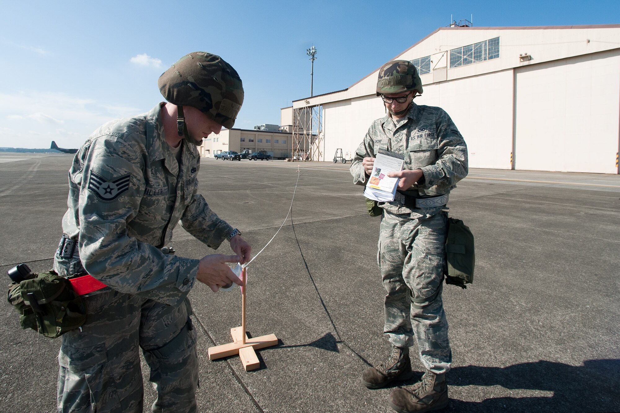 YOKOTA AIR BASE, Japan -- Staff Sgt. Anthony Miller (left) and Airman 1st Class Jake Luckt (right), both from the 374th Maintenance Squadron, set up an unexploded ordnance cordon at Yokota Air Base, Japan, Sept. 13, 2011 during a wing readiness exercise. (U.S. Air Force photo/Osakabe Yasuo)