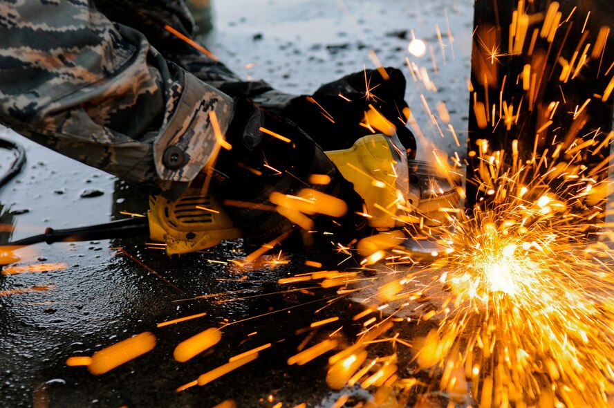 Senior Airman Christopher Gargus, 18th Civil Engineer Squadron metal shop structural journeyman, uses an angle grinder to cut down a hazardous park bench at Stearly Heights Elementary School on Kadena Air Base, Japan, Sept. 7. From fences, metal street signs and ventilation systems, to security barriers at the gates and protective shelters for the biggest Pacific fighter wing's aircraft, metal is an invaluable asset to the base and the Air Force mission. (U.S. Air Force photo/Airman 1st Class Maeson L. Elleman)