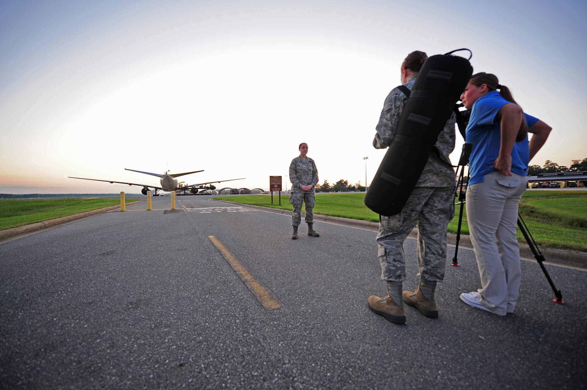 Staff Sgt. Antonia Cefalu, 4th Operations Group intelligence provider, is interviewed by Airmen 1st Class Mariah Tolbert and Samantha Konieczny near the runway on Seymour Johnson Air Force Base, N.C., Sept 10, 2011, before her deployment to Afghanistan. Crews work in the background to load all the personal cargo of the personnel that are deploying.  (U.S. Air Force photo by Senior Airman Rae Perry)