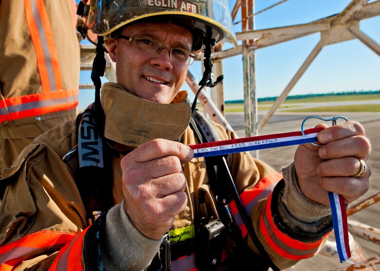 Kevin Anderson, a 96th Civil Engineer Squadron firefighter, holds up one of the streamers before attaching it to the Duke Field air traffic control tower during a 9/11 memorial stair climb at Duke Field, Sept. 11.  Thirteen firefighters commemorated the occasion by continuously climbing the steps of the ATC tower to simulate the 110-flight climb of the World Trade Center.  The firefighters hung red, white and blue streamers with the names of the 343 fallen firefighters along the tower each time they climbed.  (U.S. Air Force photo/Tech. Sgt. Samuel King Jr.)