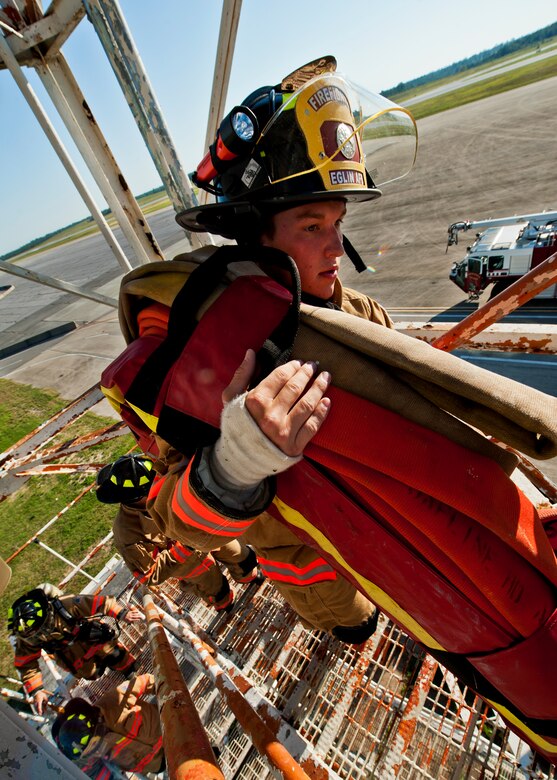 Airman 1st Class Steven Slezak, a firefighter with the 96th Civil Engineer Squadron, lugs the 50-pound, 150-foot hose up to the top of the Duke Field air traffic control tower during a 9/11 memorial stair climb at Duke Field, Sept. 11.  Thirteen firefighters commemorated the occasion by continuously climbing the steps of the ATC tower to simulate the 110-flight climb of the World Trade Center.  The firefighters hung red, white and blue streamers with the names of the 343 fallen firefighters along the tower as they climbed.  (U.S. Air Force photo/Tech. Sgt. Samuel King Jr.)