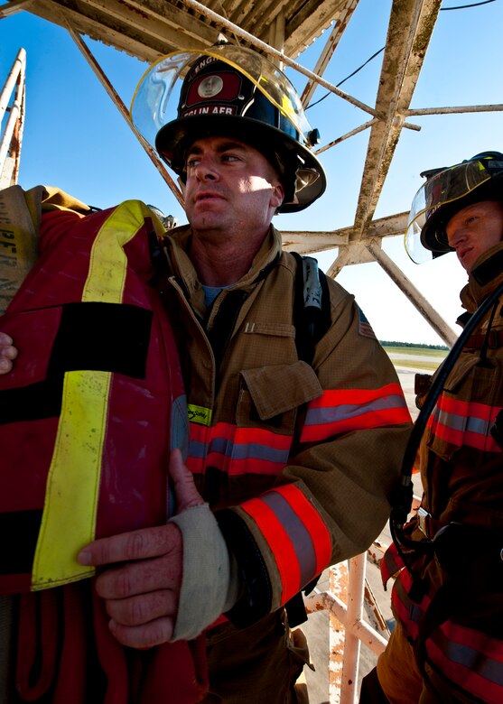 Brett Buckland, a 96th Civil Engineer Squadron firefighter, lugs the 50-pound, 150-foot hose up to the top of the Duke Field air traffic control tower during a 9/11 memorial stair climb at Duke Field, Sept. 11.  Thirteen firefighters commemorated the occasion by continuously climbing the steps of the ATC tower to simulate the 110-flight climb of the World Trade Center.  The firefighters hung red, white and blue streamers with the names of the 343 fallen firefighters along the tower as they climbed.  (U.S. Air Force photo/Tech. Sgt. Samuel King Jr.)
