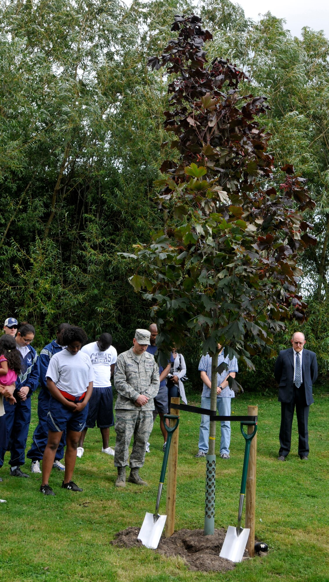 ROYAL AIR FORCE LAKENHEATH, England - Airmen and families bow heads for a moment of silence during a tree dedication ceremony to honor victims of 9/11 at Peacekeeper Park, Sept. 11, 2011. The tree dedication followed a 24-hour run that ended at 1:46 p.m. on Sept. 11, 2011, the time the first tower was hit. (U.S. Air Force photo by Senior Airman Tiffany M. Deuel)