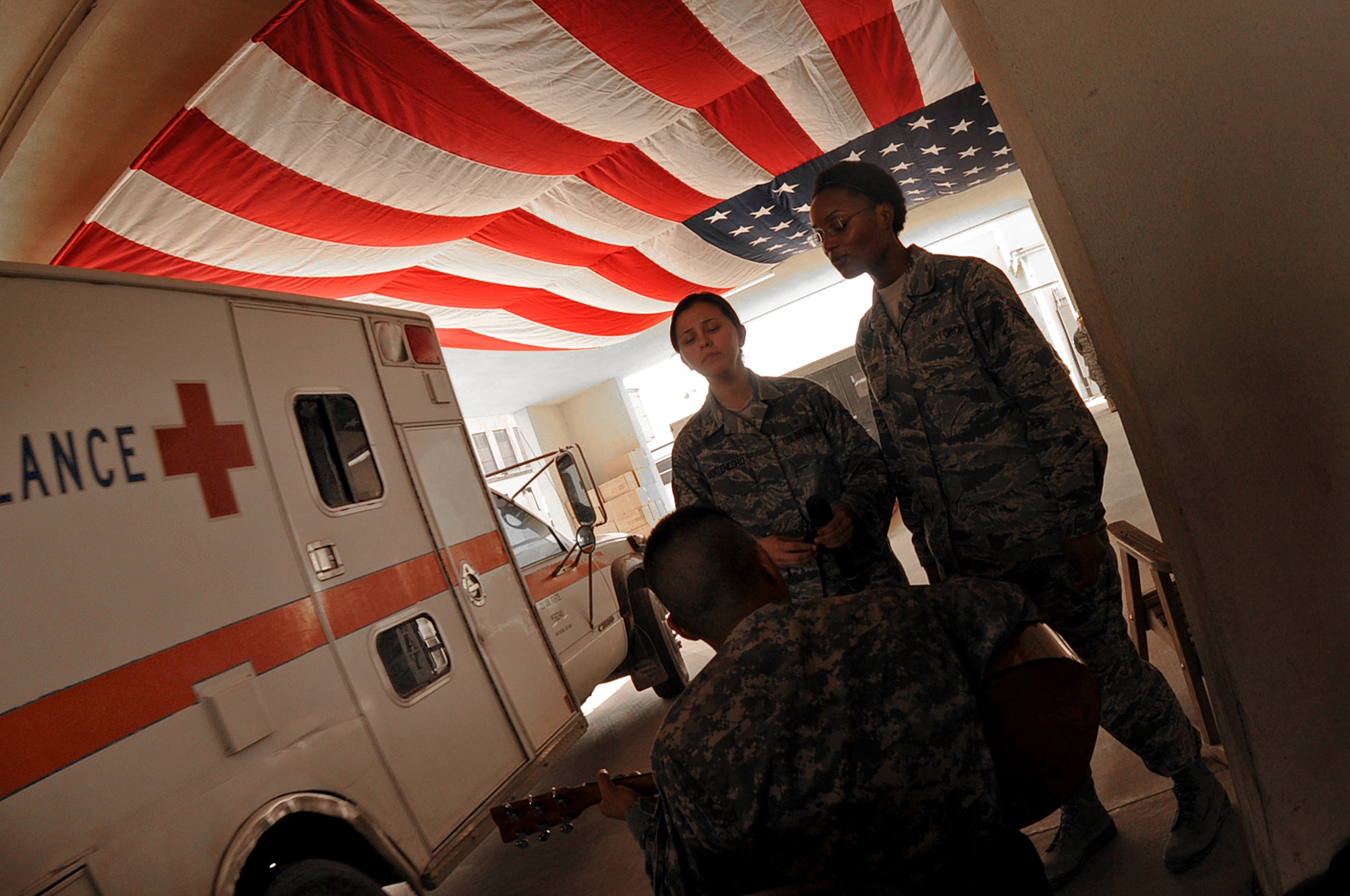 BAGRAM AIRFIELD, Afghanistan -- Staff Sgt. Lauren Montegro, 455th Expeditionary Medical Group mental health technician, Senior Airman Sabrina Carter 455th EMDG patient administration journeyman, Army Sgt. Jefferson Halili, Task Force Medical East Alpha Four, sing ‘God Bless America’ during a flag dedication ceremony at the Craig Joint Theatre Hospital here Sept. 11, 2011. (U.S. Air Force photo/ Senior Airman Krista Rose)
