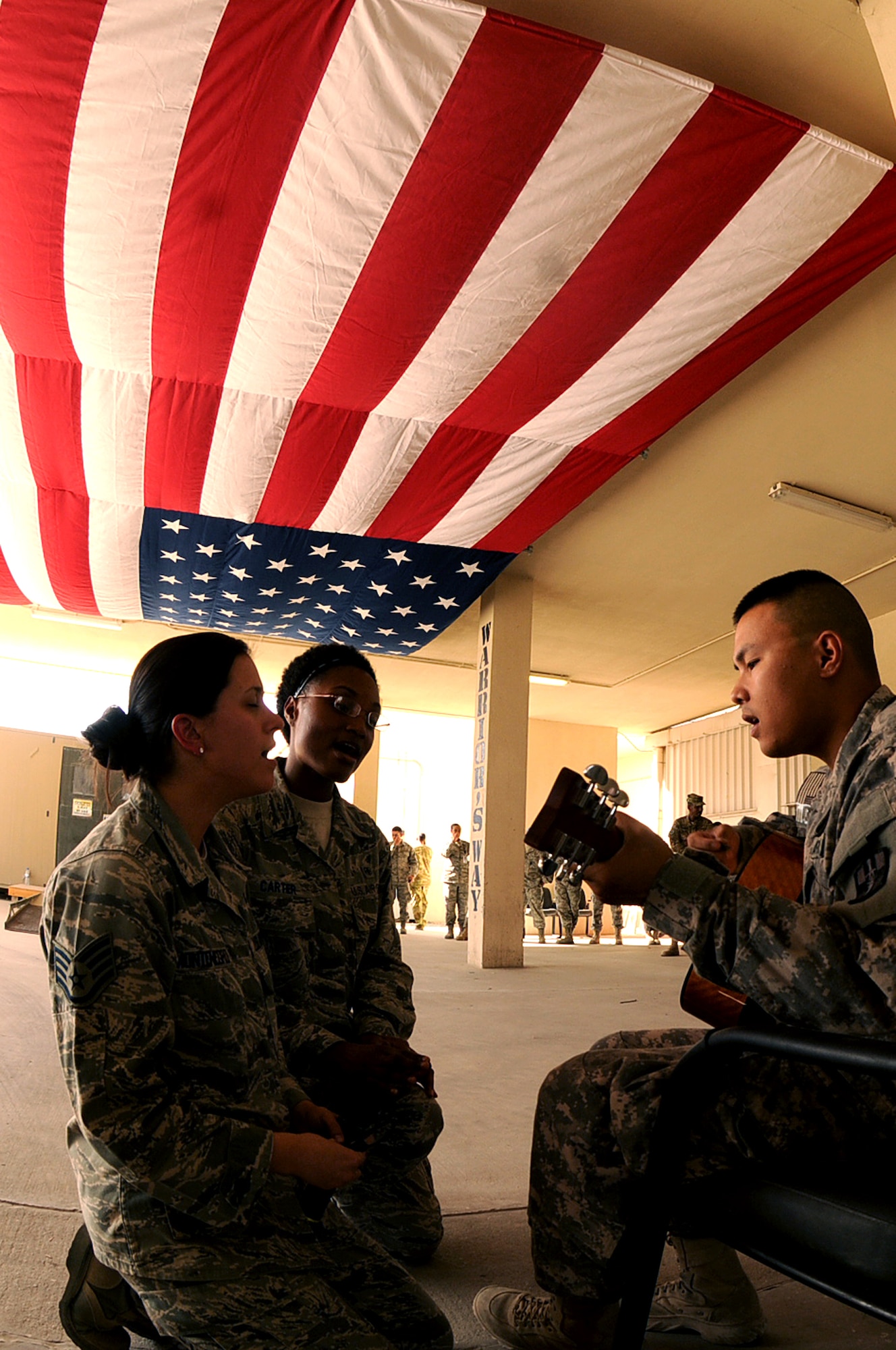 BAGRAM AIRFIELD, Afghanistan -- Staff Sgt. Lauren Montegro, 455th Expeditionary Medical Group mental health technician, Senior Airman Sabrina Carter 455th EMDG patient administration journeyman, Army Sgt. Jefferson Halili, Task Force Medical East Alpha Four, sing ‘God Bless America’ during a flag dedication ceremony at the Craig Joint Theatre Hospital here Sept. 11, 2011. (U.S. Air Force photo/ Senior Airman Krista Rose)