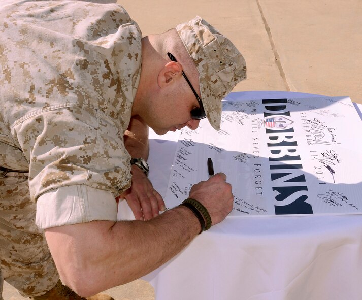 Marine Sergeant Craig Nemeth, 4th Dental Battalion, signs a 9/11 memorial poster at Dobbins Air Reserve Base; visitors were able to sign the poster throughout the day, Sept 11. In addition, a bell was rung at the exact times to mark the downing of the four aircraft and a retreat ceremony was held to honor the 10th anniversary of the 2001 terrorist attacks.   (U.S. Air Force photo/ Brad Fallin)