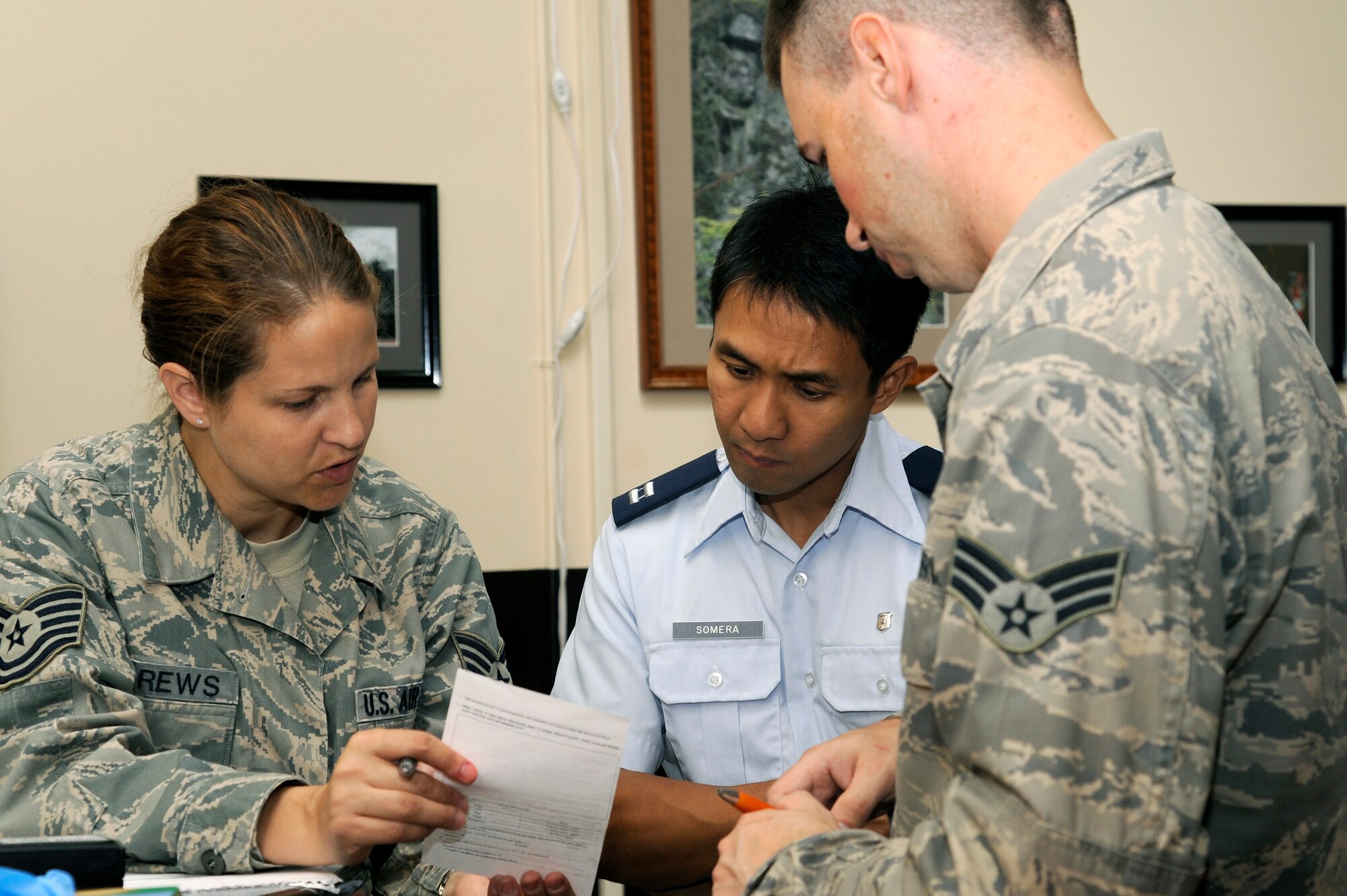 MISAWA AIR BASE, Japan - Tech. Sgt. Laura Andrews, left, Capt. Leonardo Somera, center, and Senior Airman Donary Scully, 35th Aerospace Medicine Squadron, go over paperwork during a biological response exercise at building 99 here Sept. 12. The exercise kicked off after a medical logistics worker discovered an individual reaching into the intake vent in the ceiling with an electrical cord hanging out. (U.S. Air Force photo/Tech. Sgt. Marie Brown)
