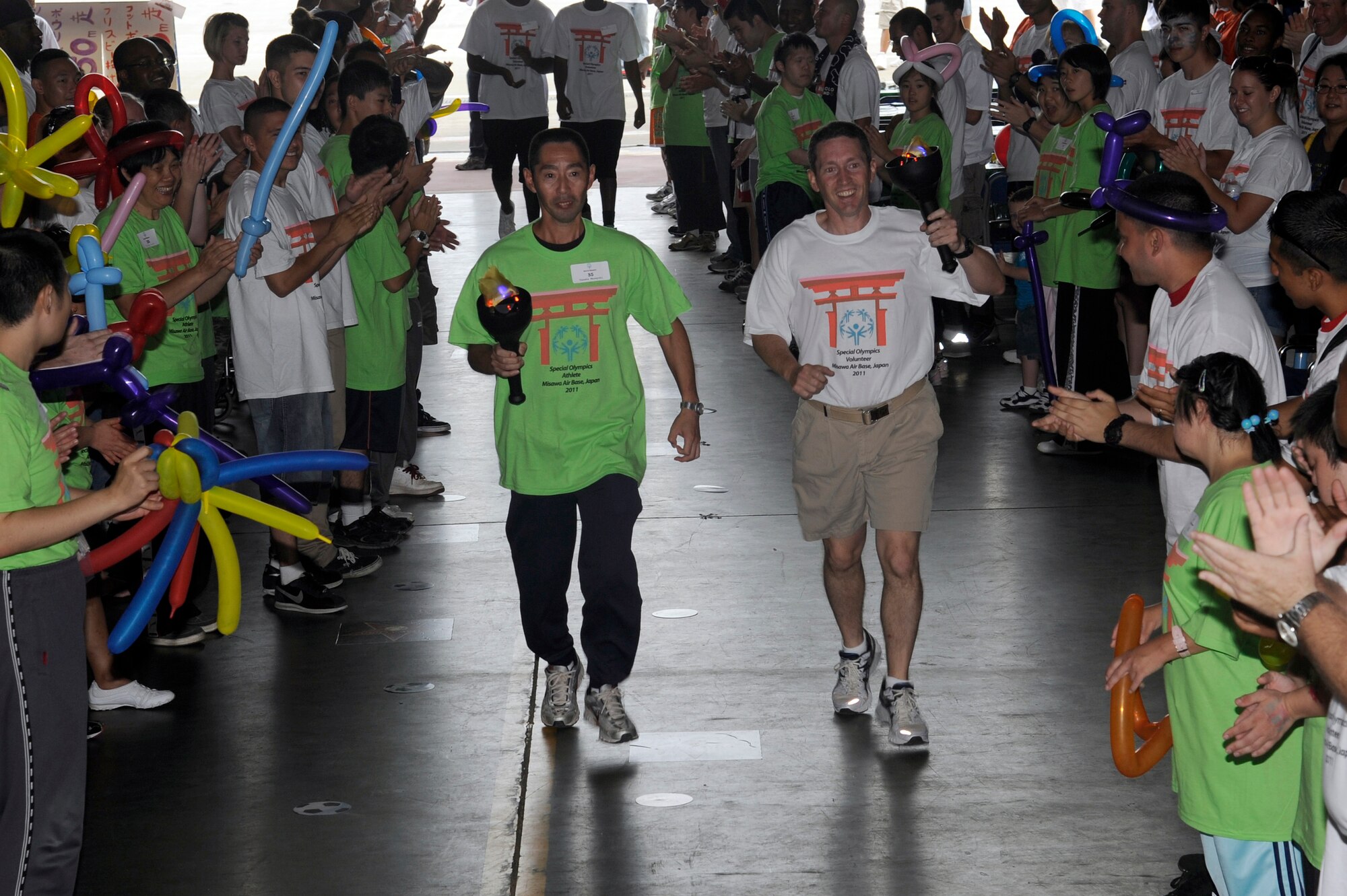MISAWA AIR BASE, Japan - Tanaka Masayuki, left, and U.S. Air Force Col. Michael D. Rothstein, 35th Fighter Wing commander, runs the Olympic torch into Hangar 949, kicking off the annual Special Olympics here Sept. 10. Athletes participated in various activities including a 25- and 50-meter dash, bowling, soccer kick and basketball toss. (U.S. Air Force photo/Tech. Sgt. Marie Brown)