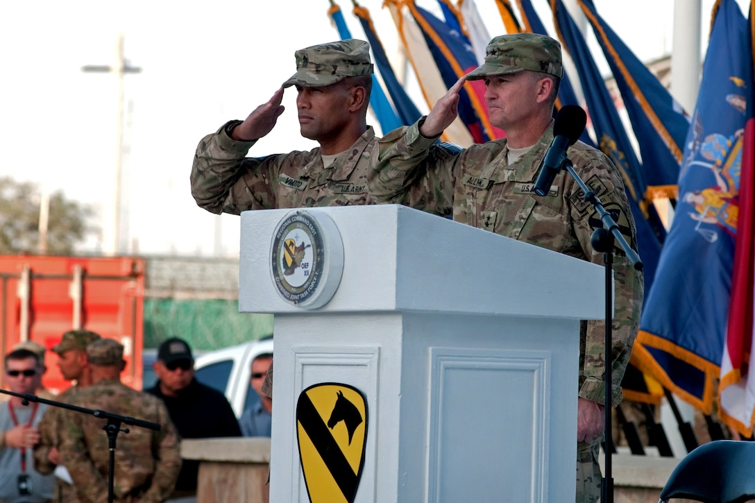 U.S. Command Sgt. Major Isaia Vimoto, left, and Army Major Gen. Daniel Allyn salute the colors during a ceremony in Bagram, Afghanistan, Sept. 2011, remembering the attacks of 9/11. Vimoto is the command sergeant major and Allyn is the commander of Regional Command East. A remnant from ground zero stands tall among NATO flags to serve as a constant reminder to all those who visit the Regional Command East headquarters.