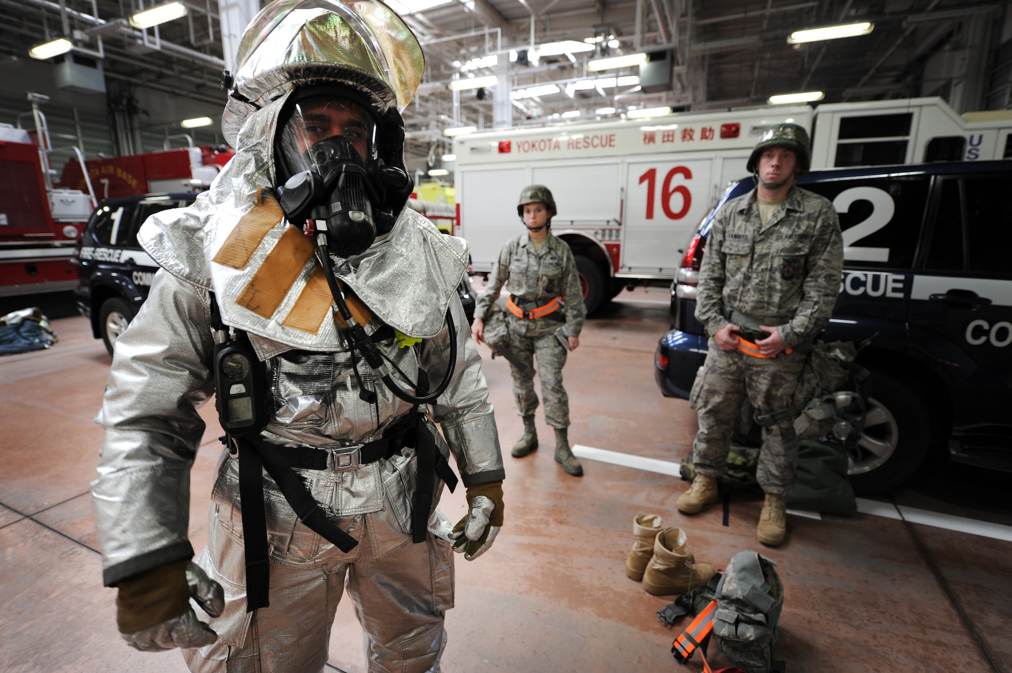 YOKOTA AIR BASE, Japan – Airman 1st Class Christopher Diaz, a firefighter in the 374th Civil Engineer Squadron, demonstrates how to wear the additional gear required for firefighters to respond in a chemical environment at Yokota Air Base, Japan, Sept. 13, 2011. Yokota recently participated in an operational readiness exercise.(U.S. Air Force photo/Staff Sgt. Stacy Moless)