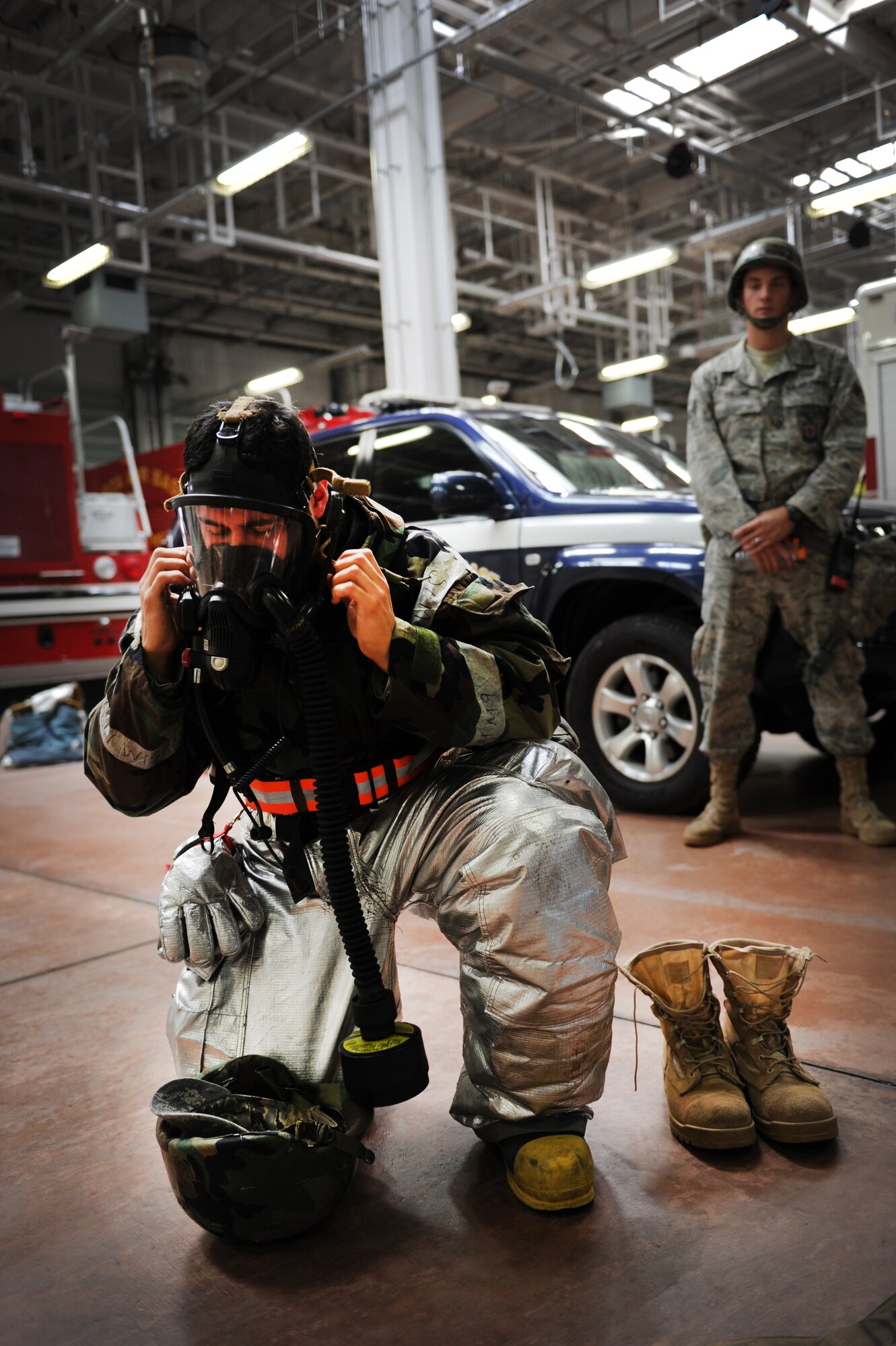 YOKOTA AIR BASE, Japan – Airman 1st Class Christopher Diaz, a firefighter in the 374th Civil Engineer Squadron, demonstrates how to wear the additional gear required for firefighters to respond in a chemical environment at Yokota Air Base, Japan, Sept. 13, 2011. Yokota recently participated in an operational readiness exercise. (U.S. Air Force photo/Staff Sgt. Stacy Moless)