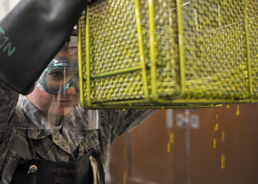 Airman 1st Class Nicole Calungsod, 51st Maintenance Squadron nondestructive inspection technician, lifts aircraft parts from a special oil-based dye called penetrant Sept. 13, 2011. NDI is the examination of aerospace weapon systems components and support equipment for structural integrity using nondestructive inspection methods and fluid analysis.  (U.S. Air Force Photo by/ Senior Airman Adam Grant) 