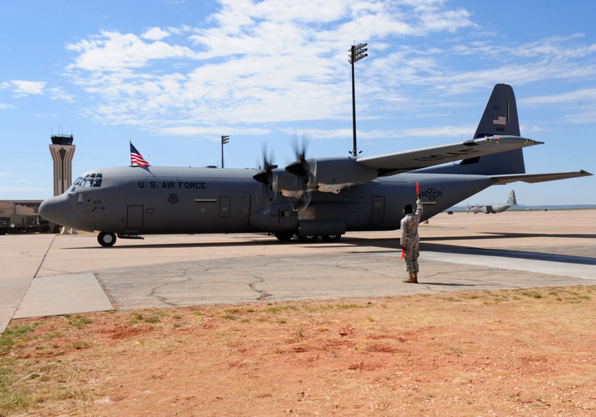 DYESS AIR FORCE BASE, Texas - A marshaller brings in the 317th Airlift Group's newest C-130J here Sept. 8. The delivery, by Lt. Gen. Robert R. Allardice, Commander, 18th Air Force, was the sixth in the 317th's continuing transition to the new aircraft. Dyess is slated to become home to the Air Force's largest C-130J fleet when it receives its 28th and final C-130J in 2013.