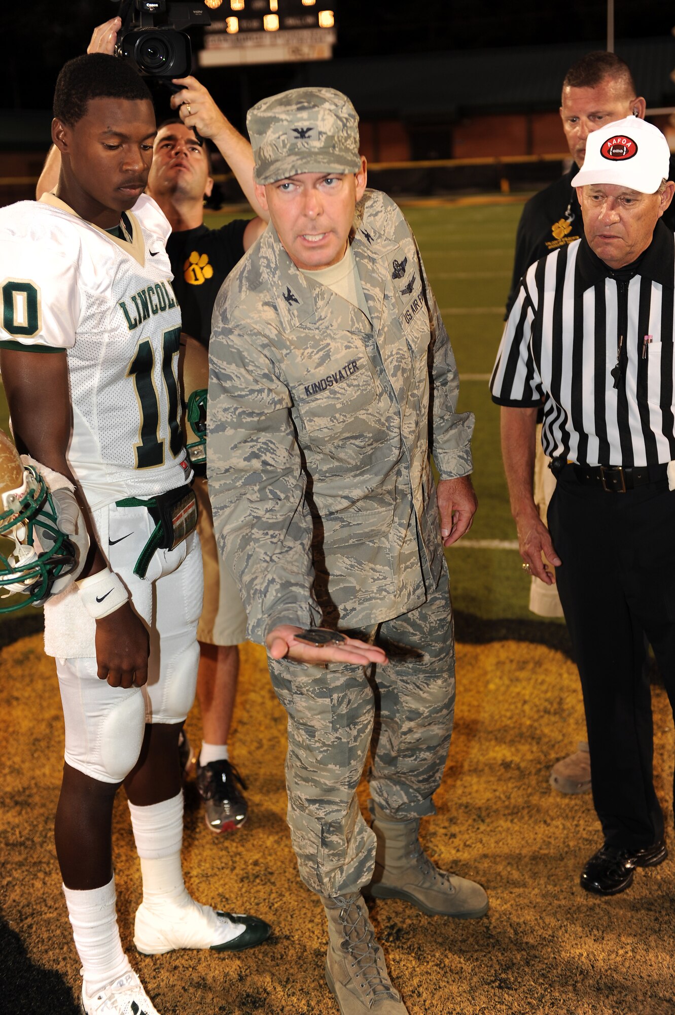 U.S. Air Force Col. Scott Kindsvater, 93rd Air Ground Operations Wing commander, shows players from Lincoln and Valdosta High Schools the special coin to be used in the coin toss at Cleveland Field, Valdosta, Ga., Sept. 9, 2011.  VHS won the coin toss and elected to receive the ball for the initial kickoff. (U.S. Air Force photo Senior Airman Ciara Wymbs/Released) 