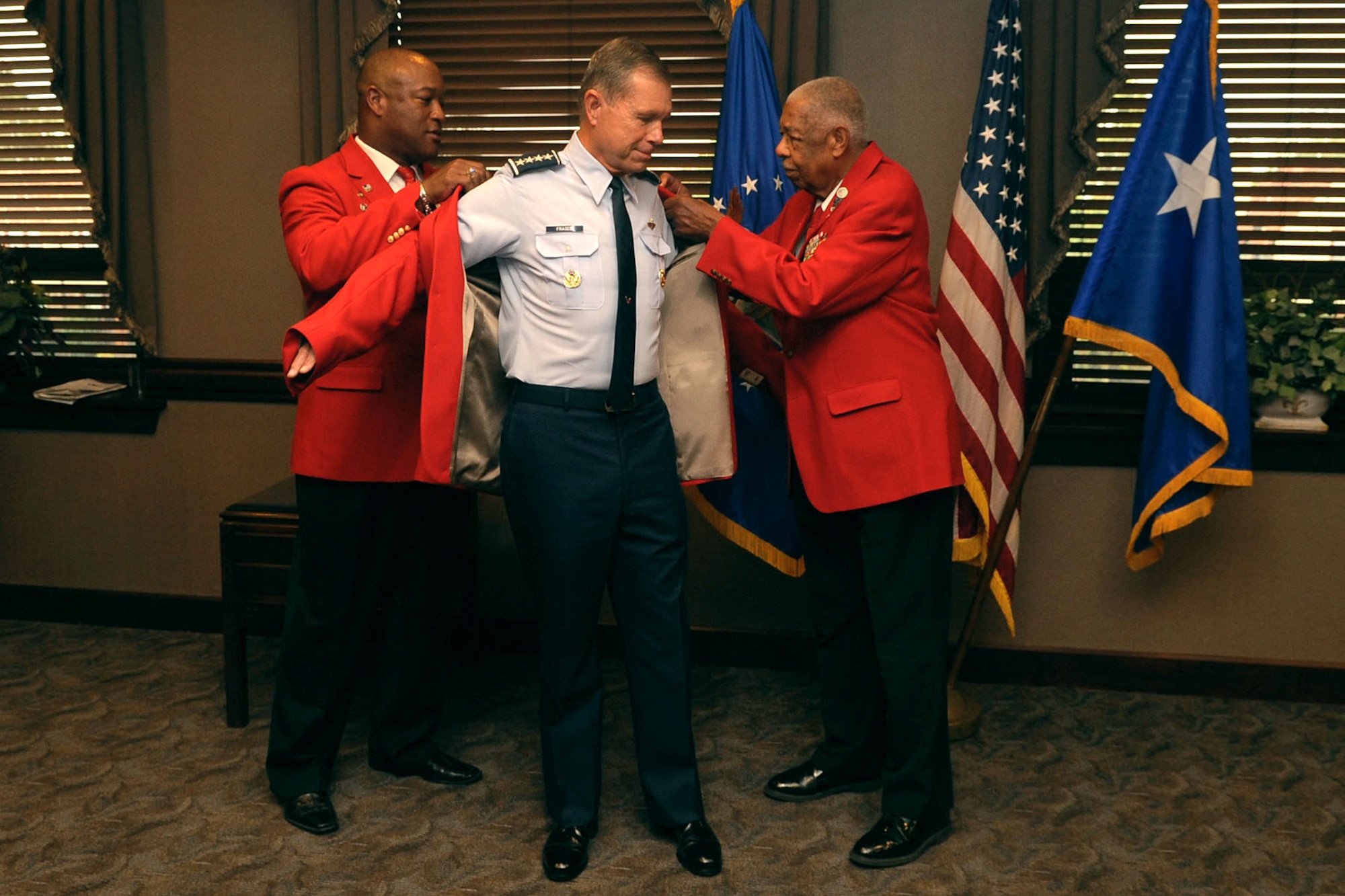T.J. Spann, Tidewater Chapter-Tuskegee Airmen Incorporated president, and Grant Williams Sr, Tidewater Chapter-Tuskegee Airmen Incorporated speakers bureau chairman, help U.S. Air Force Gen. William M. Fraser III, commander of Air Combat Command, put on his red jacket during the Honorary Tuskegee Airmen event at Langley Air Force Base, Va., Sept. 8, 2011. The jacket is a historical nod to the Red Tail P-51 flown by the Tuskegee Airmen, who were supported by nearly 19,000 Tuskegee Airmen ground-support forces.  (U.S. Air Force photo by Airman 1st Class Racheal Watson/Released)
