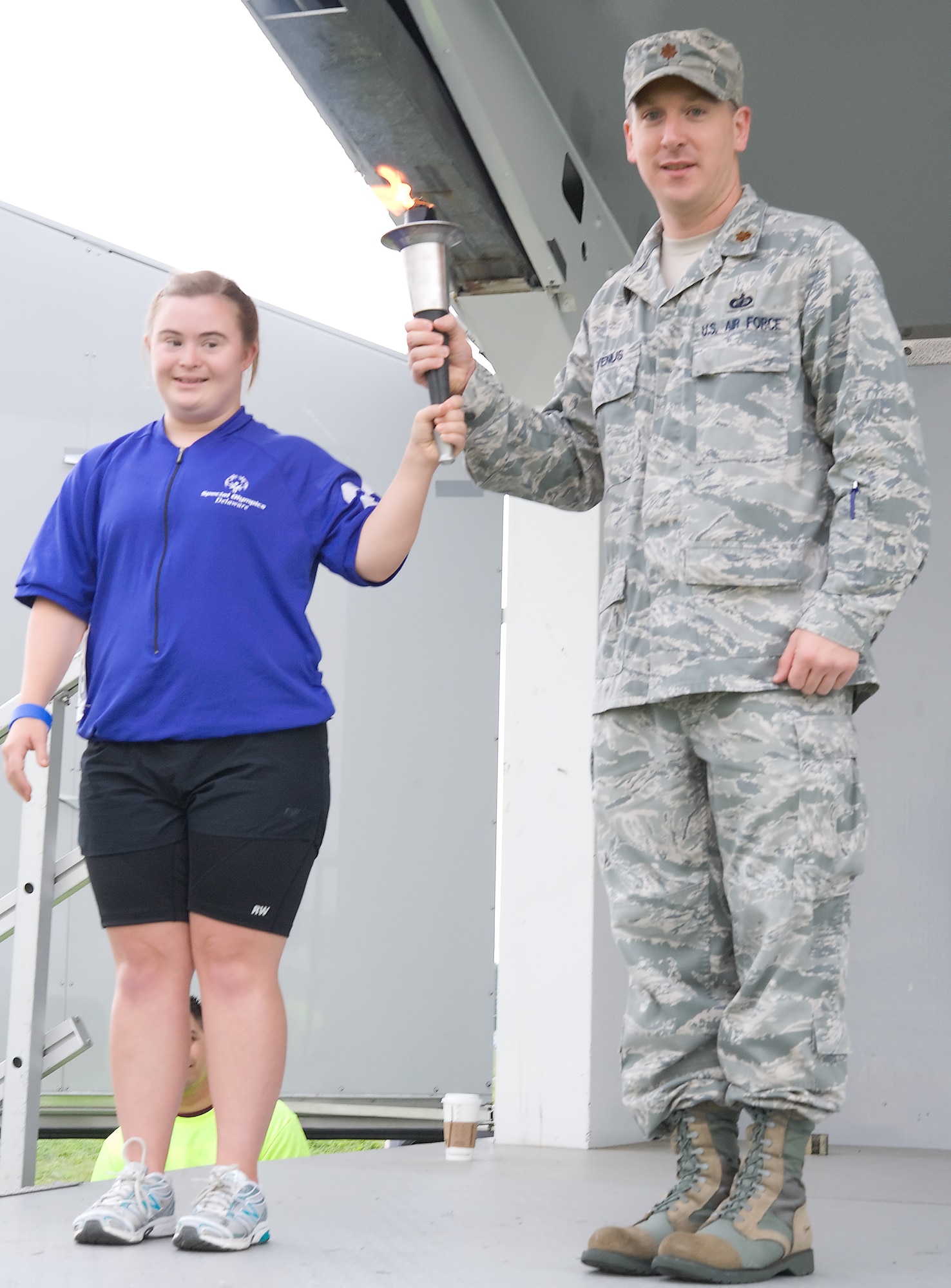Maj. Michael Venus, the commander of the 436th Comptroller Squadron, presents Betsy Long, of the Special Olympics Maryland Upper Shore bicycling team, with the Special Olympics torch during the opening ceremonies Sept. 10, 2011, at Dover Air Force Base, Del. (U.S. Air Force photo by Airman 1st Class Kathryn Stilwell)