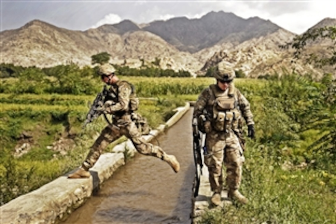 U.S. Army Spc. Jake Amato jumps over a canal while he and his teammate, Sgt. Sean Matthews, look for triggermen in the Alisheng district of Afghanistan's Laghman province, Sept. 12, 2011. Amato and Matthews are assigned to the Laghman Provincial Reconstruction Team. The team, which partnered with the security forces assistant team and the Afghan police, patrolled through a village to talk to residents and teach the police proper patrol procedures.