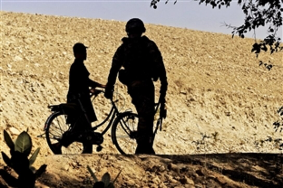 U.S. Army Sgt. Sterling Shearer walks with an Afghan boy in the Alisheng district in Afghanistan's Laghman province, Sept. 12, 2011. Shearer is assigned to the Laghman Provincial Reconstruction Team, which patrolled a village with Afghan police to teach proper patrol procedures and talk to residents.