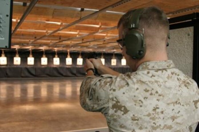 Cpl. Justin L. Carter, Indoor Small Arms Range ammo noncommissioned officer, draws down on a target as he prepares to fire at the ISAR here Sept. 14 during the Combat Marksmanship Training Course. The course focuses on teaching Marines proper stance and firing techniques associated with pistol qualifications.