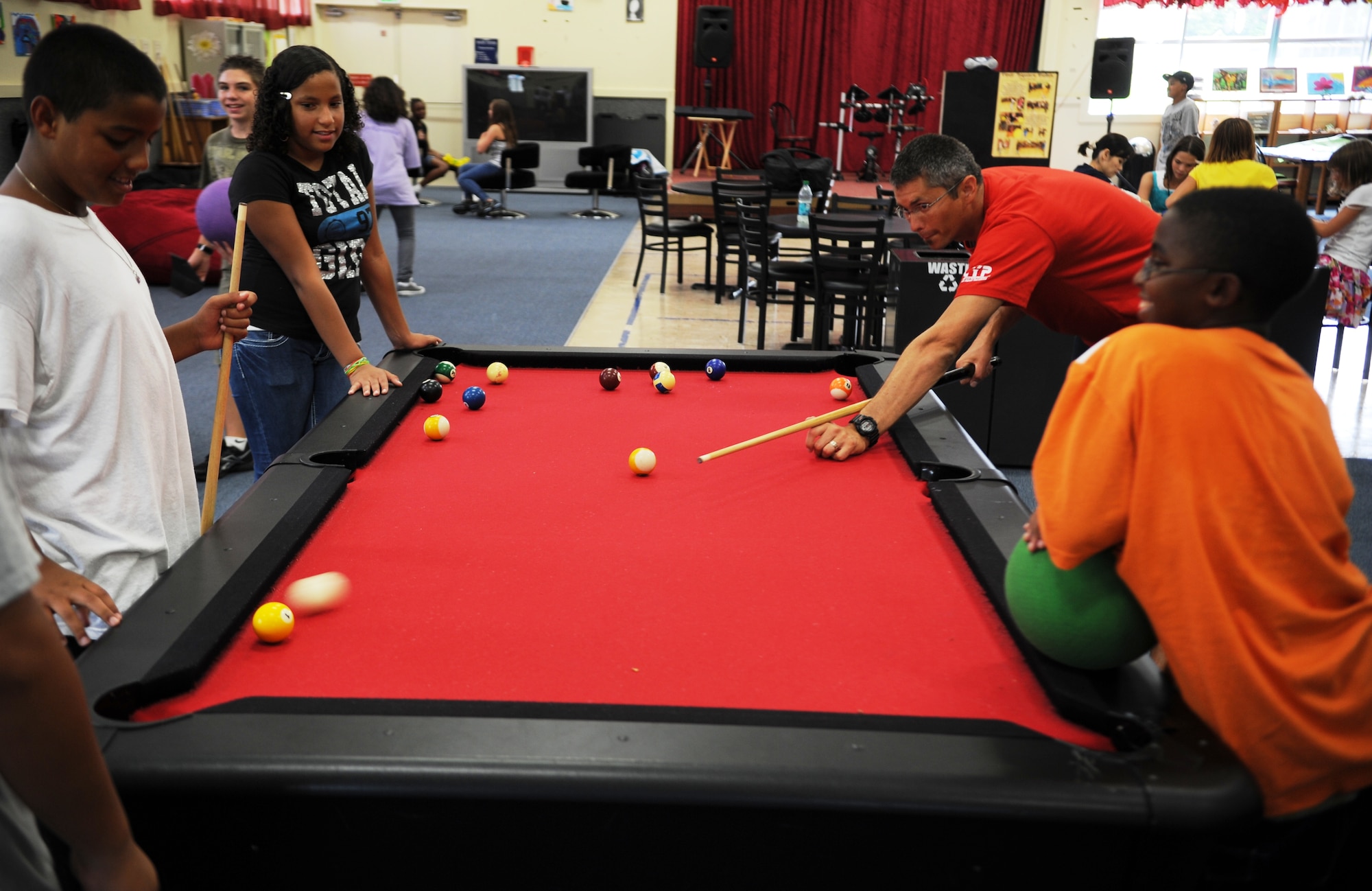 Geoffrey Rhinehart, Kadena Youth Center director, shoots pool with children at the center on Kadena Air Base, Japan, Sept. 8. As the former Misawa Air Base, Japan, Youth Programs director, Rhinehart is no stranger to ensuring the youth center is a positive place for youth to hang out and get involved. (U.S. Air Force photo/Staff Sgt. Christopher Hummel)