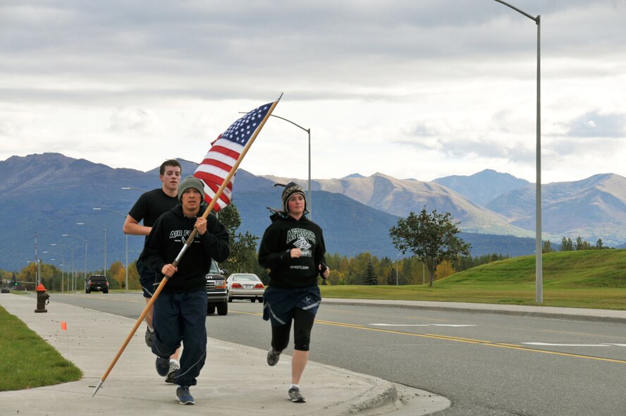 Senior Airmen Chris O'Brien, an Arctic Reservist with the 477th Aircraft Maintenance Squadron carries the flag in a formation run in honor of 9/11 on Joint Base Elmendorf-Richardson. The 24-hour run was sponsored by the Arnold Air Society from the University of Alaska at Anchorage. 