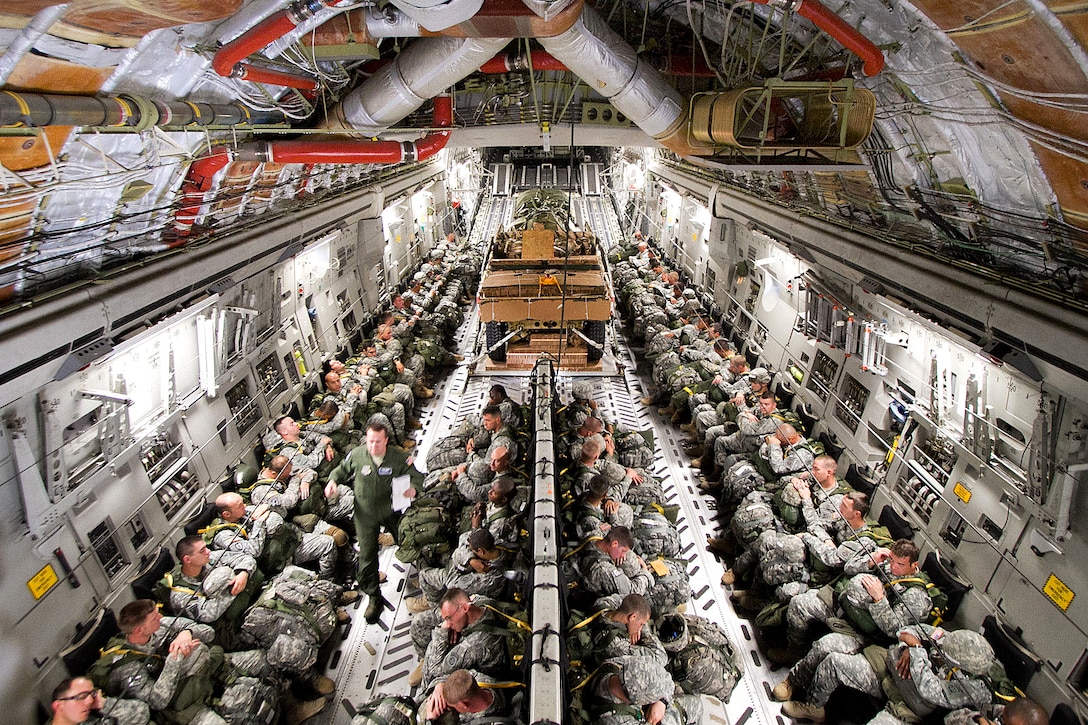 Paratroopers await takeoff as they sit next to a Humvee and 105mm howitzer in the cargo hold of a C-17 Globemaster III aircraft on Pope Field, N.C., Sept. 10, 2011. During the training exercise, crews will use parachutes to transport the heavy equipment from the plane to the drop zone on first pass. The paratroopers will jump on the second pass.