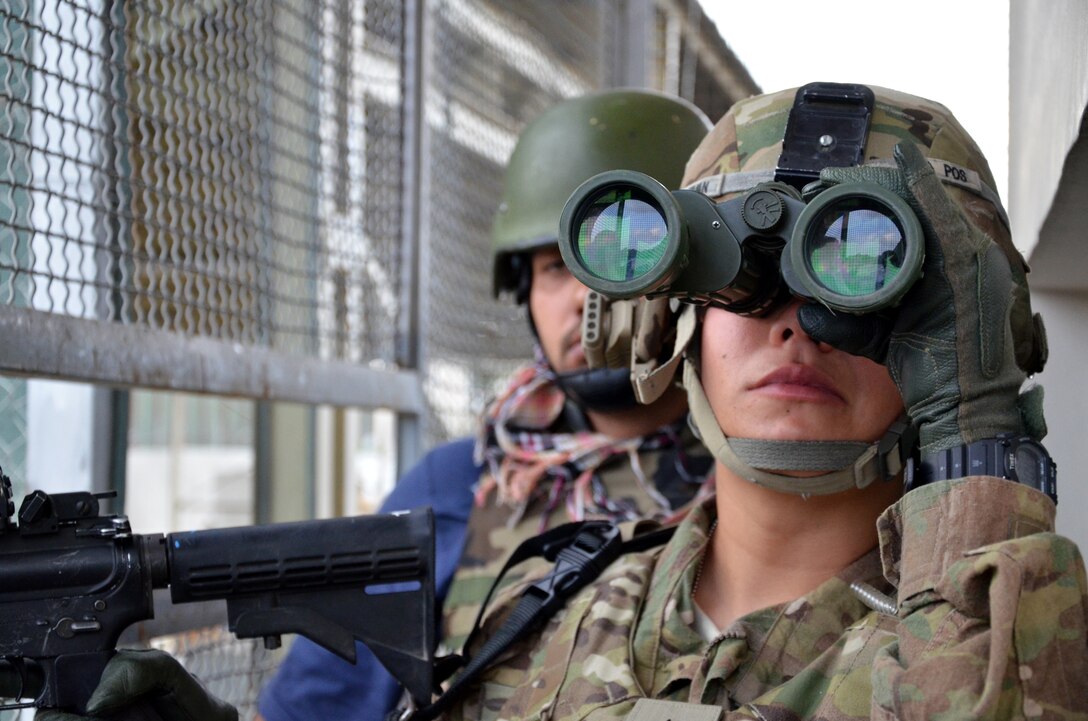 U.S. Army Sgt. Jaclyn Guzman maintains visual surveillance as shots are fired and explosions erupt from a building in Kabul, Afghanistan, Sept. 13, 2011. Afghan and coalition forces trapped the insurgents in the partially-constructed building they were using as a firing position, and conducted a floor-by-floor clearing operation. Guzman is assigned to the U.S. Forces Afghanistan Protective Service Detail.