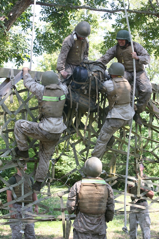 Marine students from Marine Corps Martial Arts Instructor Course 1-11 work together to get the mission pack across an obstacle during the final event of the Marine Corps Martial Arts Instructor Course here, Sept. 14, 2011. Each squad was assigned a mission pack that they had to carry throughout the day. The pack substituted the gear that Marines have to bring out on the patrols when they are deployed. The 15-day course prepared the Marines for the rigorous final event in which they endured eight hours of combat conditioning, ground fighting, and hiking more than six miles with a full combat load.