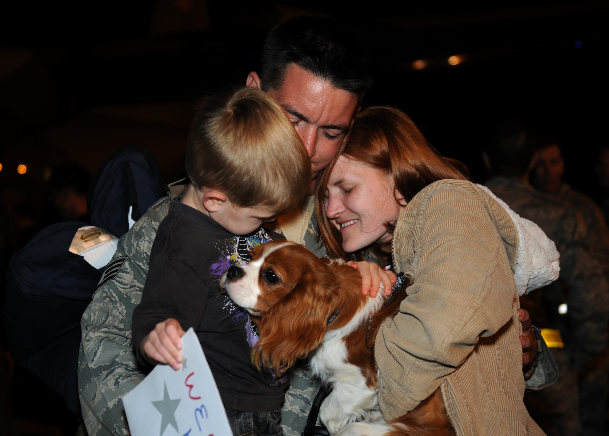 ROYAL AIR FORCE LAKENHEATH, England - Staff Sgt. Michael Prince, an electrical/environmental specialist with the 748th Aircraft Maintenance Squadron, hugs his wife, Staff Sgt. Ronda Prince, a supply manager with the 100th Logistics Readiness Squadron at RAF Mildenhall, his 3-year-old son, Aden, and their dog, Stuart, after returning from consecutive deployments Sept. 15, 2011. Approximately 60 Airmen from the 56th Rescue Squadron and 748th Aircraft Maintenance Squadron returned home after back-to-back deployments lasting more than nine months in support of Operations Enduring Freedom, Odyssey Dawn and Unified Protector. (U.S. Air Force photo by Airman Cory D. Payne)

