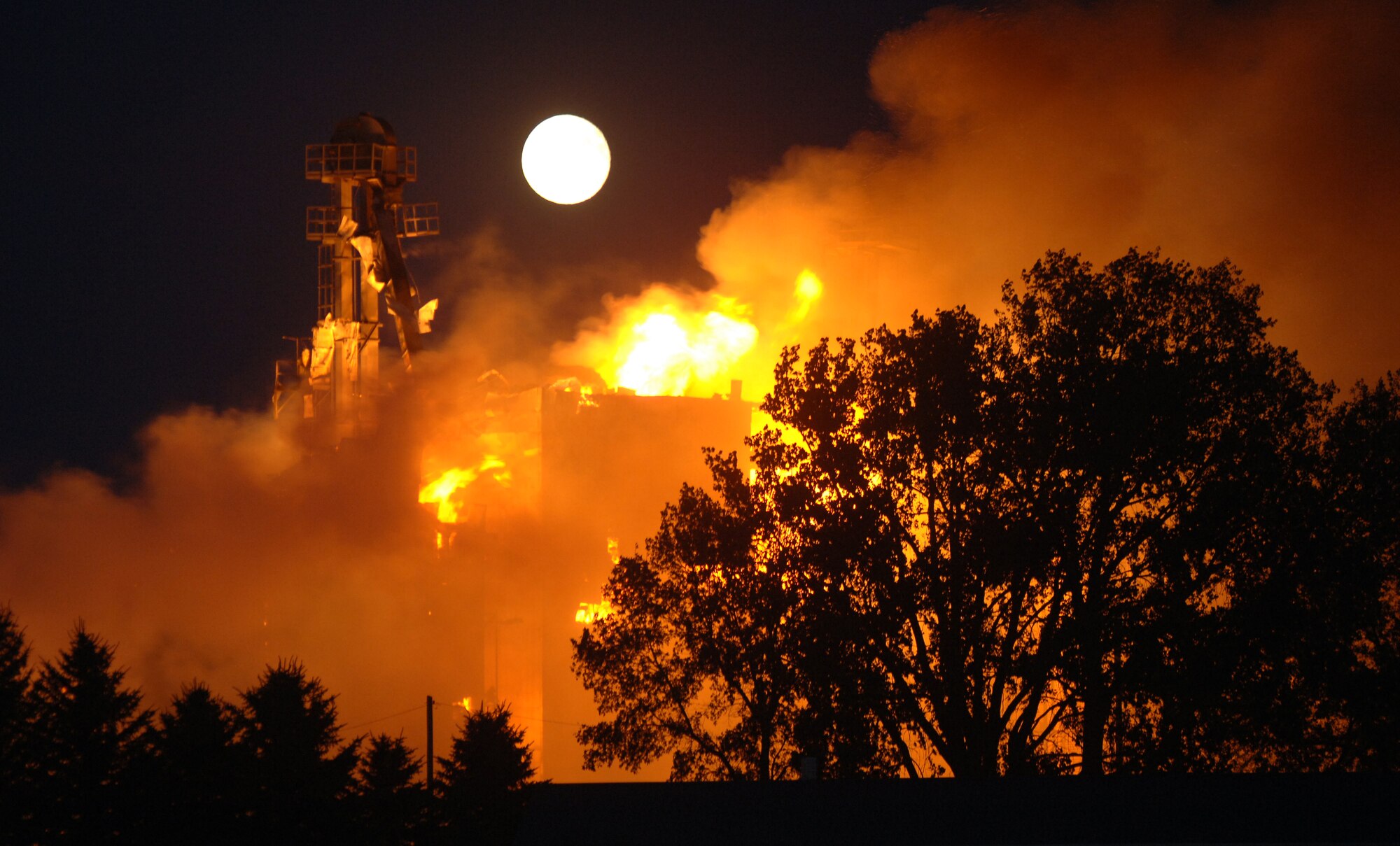 A full moon rises over the Forest River Farmers Elevator, about 20 miles north of Grand Forks Air Force Base, N.D., as it burns brightly on Sept. 13. Firefighters from the base, along with several other local communities, delivered thousands of gallons of water to help battle the blaze. (U.S. Air Force photo/Tim Flack)
