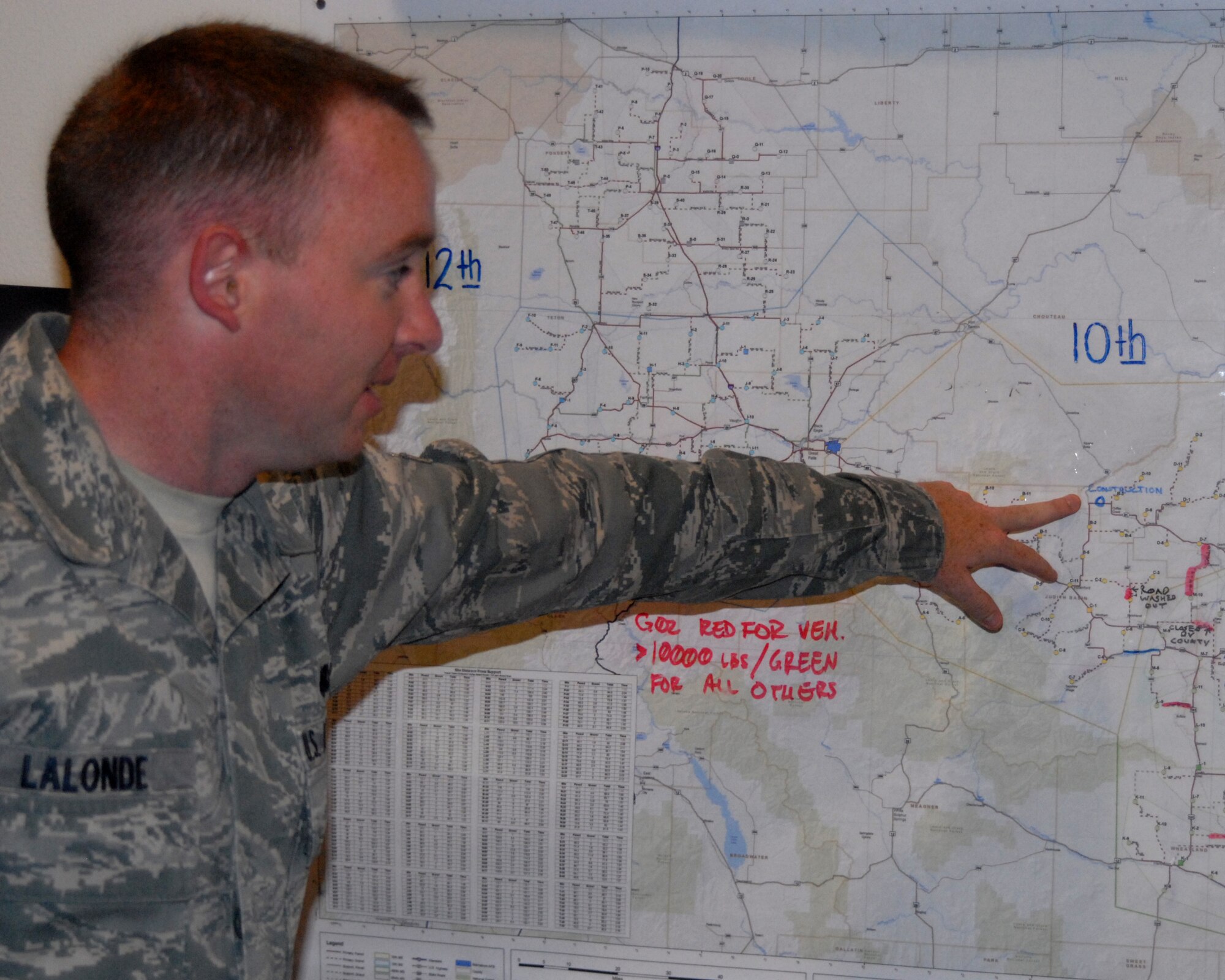 Airman 1st Class Casey LaLonde points to a map of the area the Malmstrom AFB Traffic Control Center supports. (U.S. Air Force photo by Airman Nikolas Asmussen)