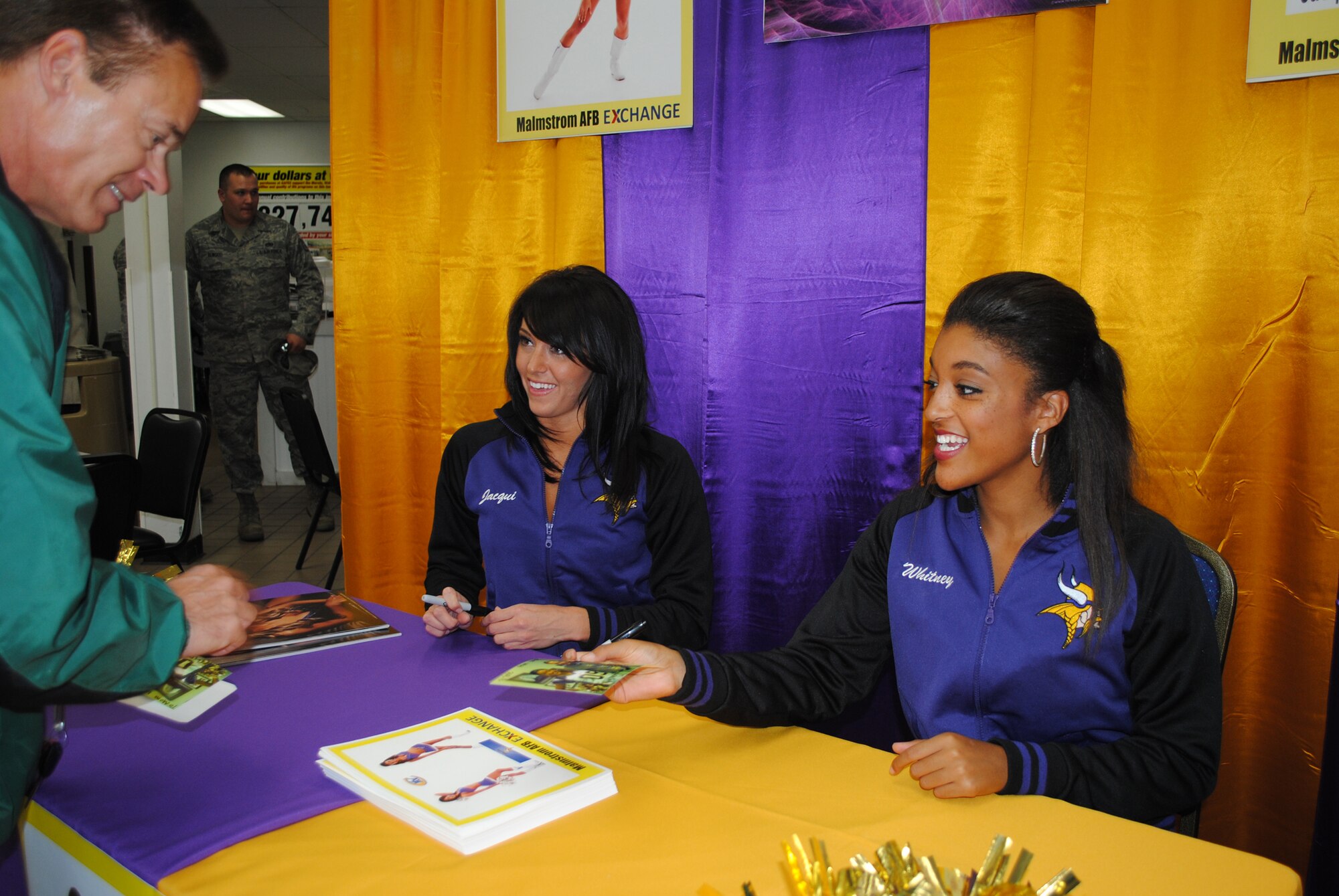 Jaqueline and Whitney, both members of the Minnesota Vikings cheerleading team, sign photos for fans during their visit to the Malmstrom Exchange Sept. 8.  (U.S. Air Force photo/Airman 1st Class Katrina Heikkinen)